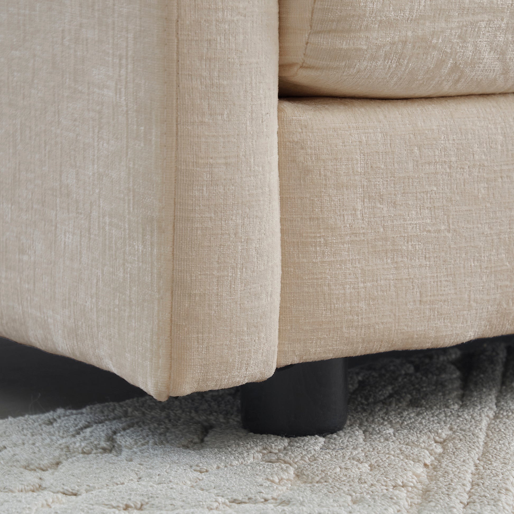 Closeup of beige textured fabric on a modern sofa corner with black legs
