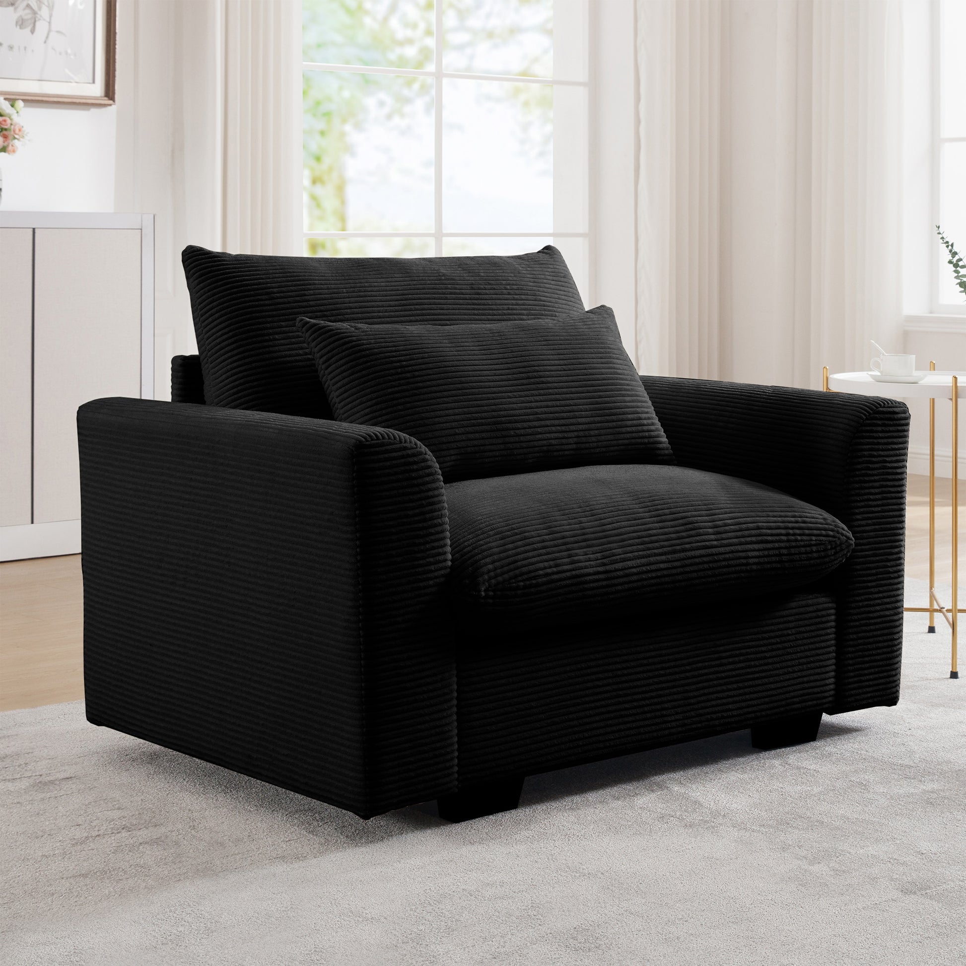 Plush black corduroy armchair with deep seating and a lumbar pillow perfect for a cozy living room