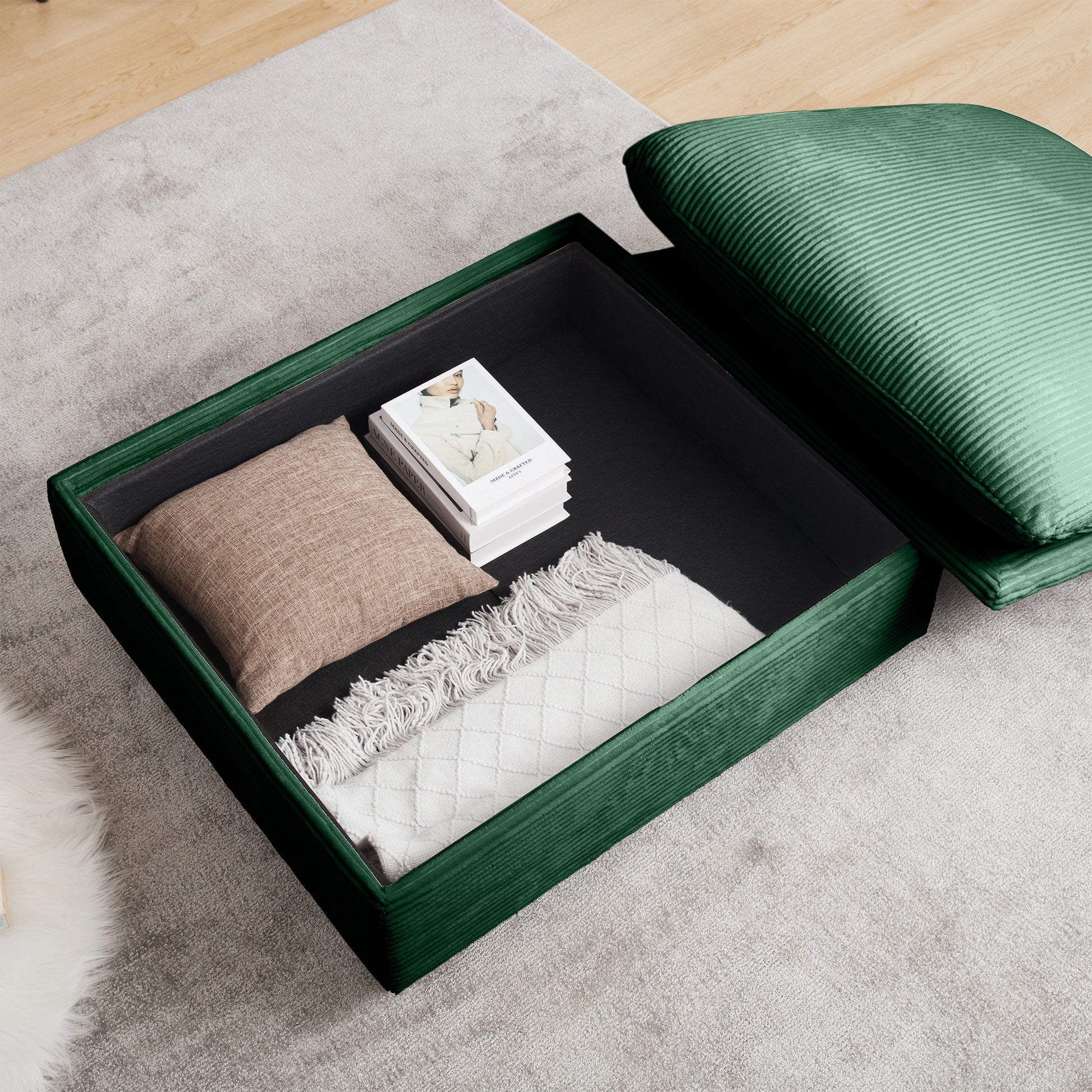 Emerald green velvet storage ottoman with corduroy texture open to reveal books and blankets