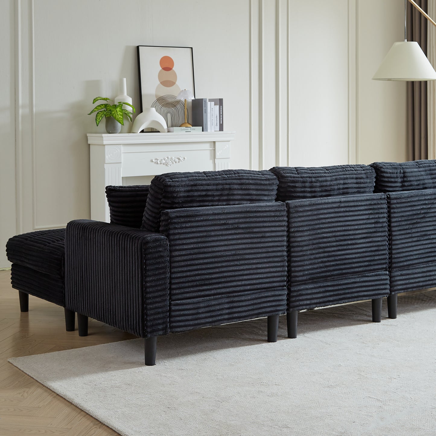 Dark grey corduroy sectional sofa with chaise lounge and black legs in a modern living room