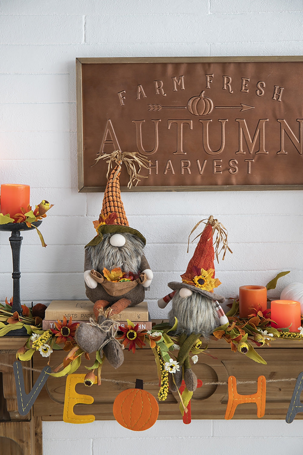 Two plush fall gnomes with burlap hats one holding a basket of autumn leaves and berries