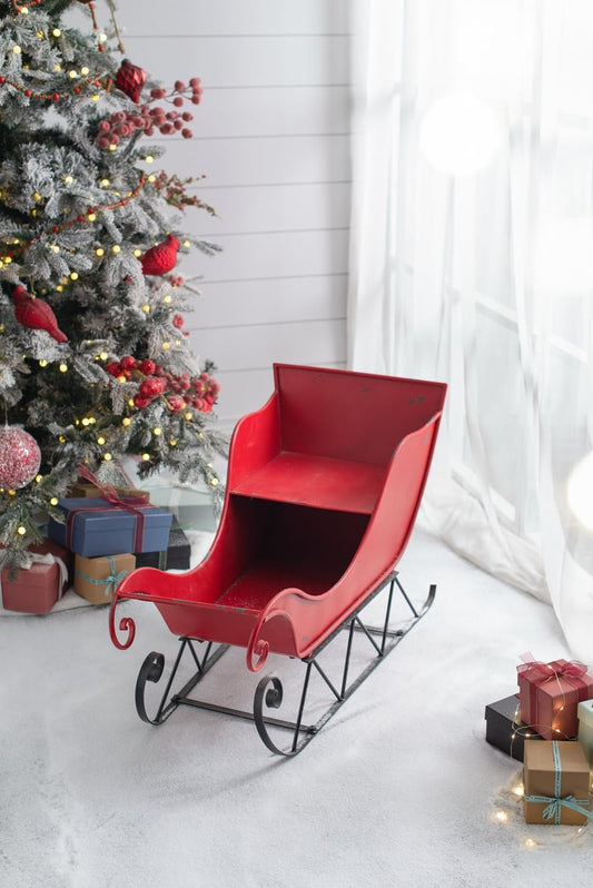 Vintage red metal sleigh with decorative scrolls perfect for holiday decor