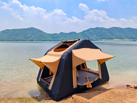 Black and tan popup camping tent set up at the edge of a calm lake