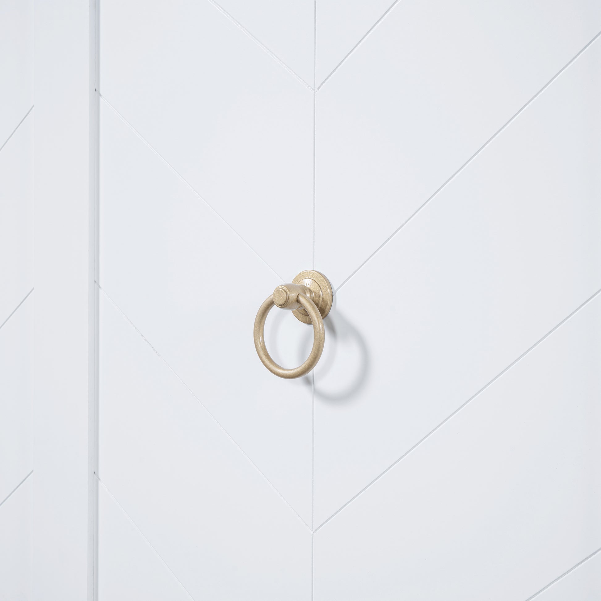 Antique brass ring pull on a white chevron patterned door