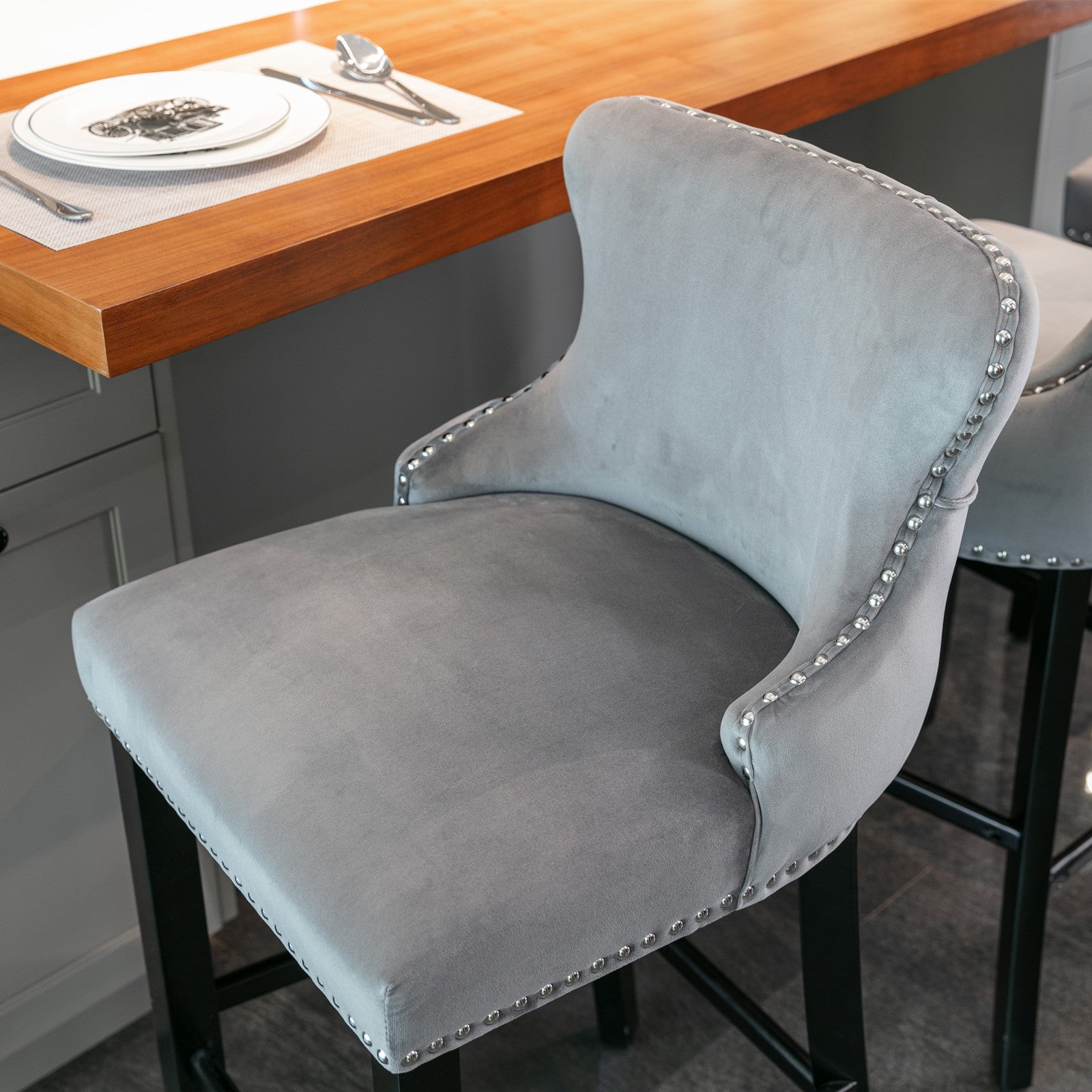 Grey velvet bar stool with silver nailhead trim and curved back