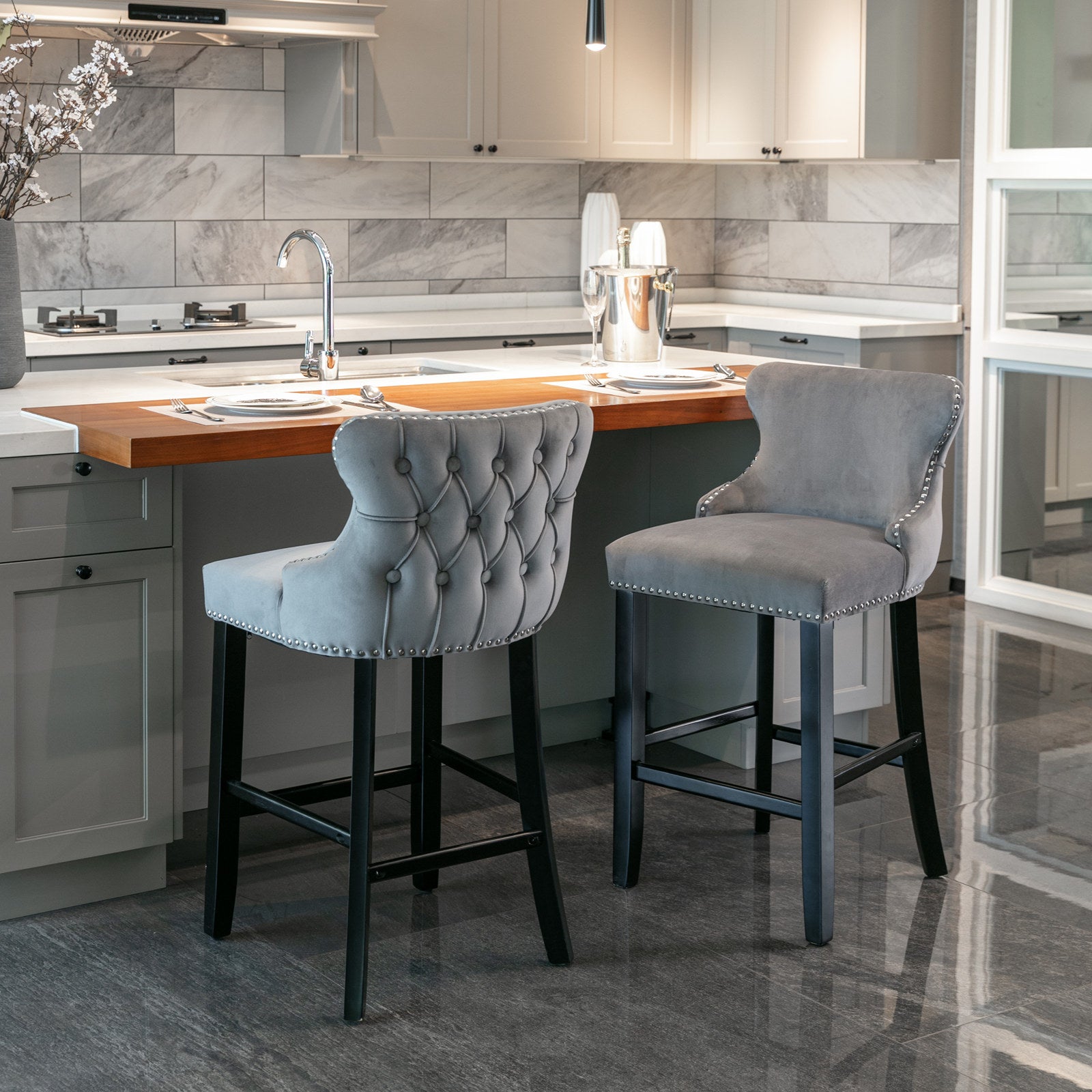 Gray tufted velvet bar stool with silver nailhead trim and dark wood legs