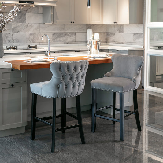 Gray tufted velvet bar stool with silver nailhead trim and dark wood legs