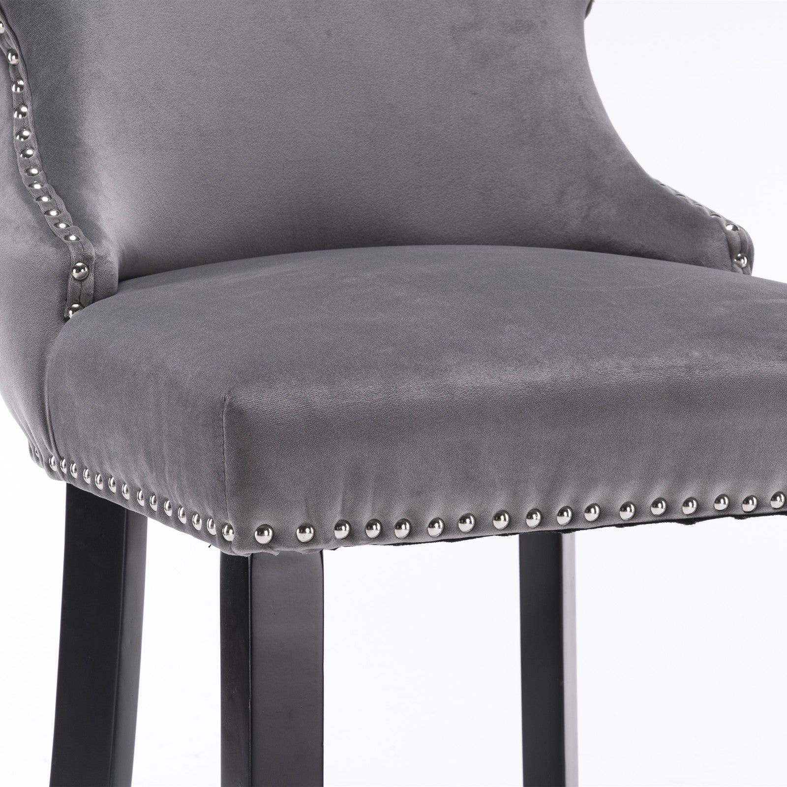 Closeup of grey velvet bar stool with silver nailhead trim and black legs