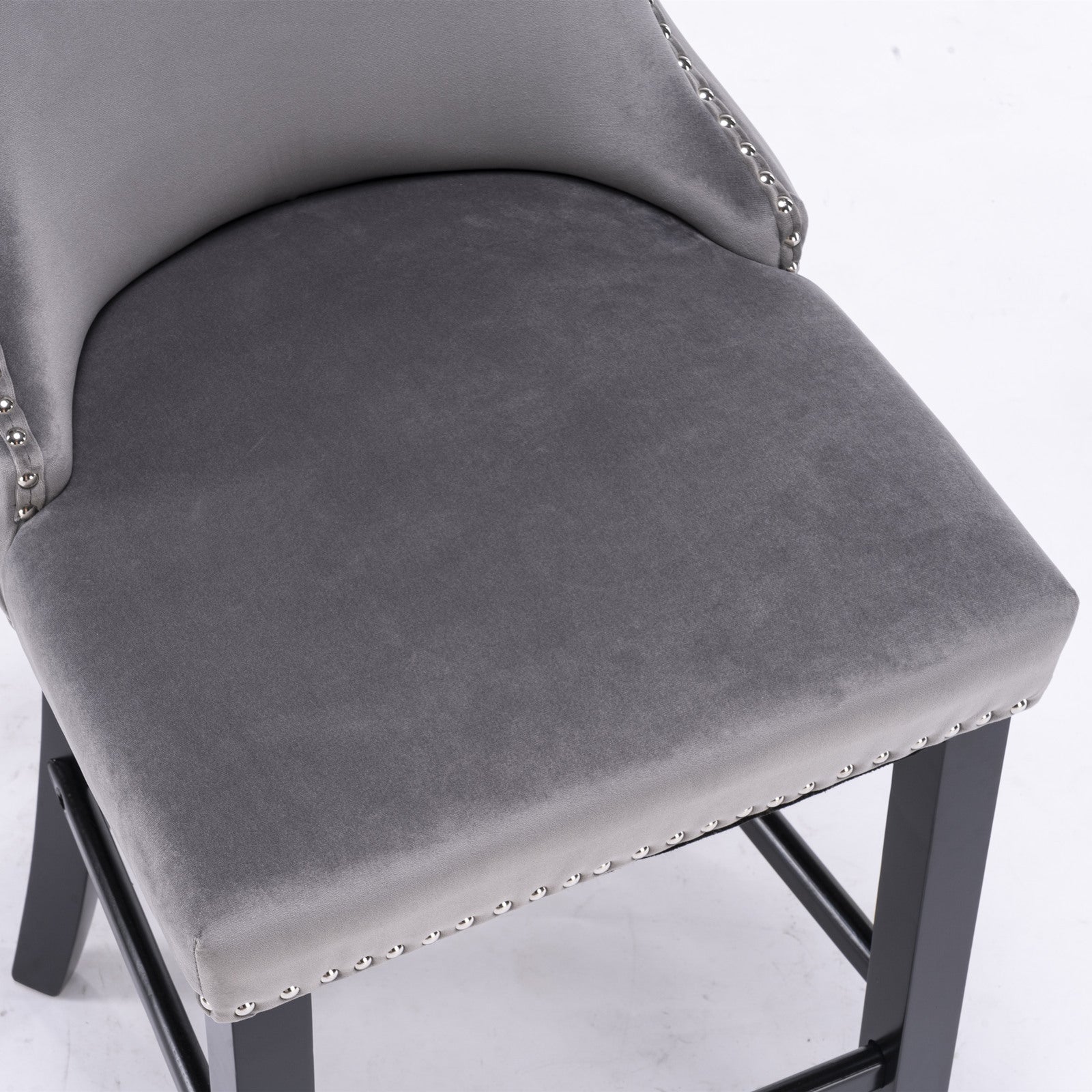 Closeup of a plush grey velvet bar stool with silver nailhead trim and dark wood legs