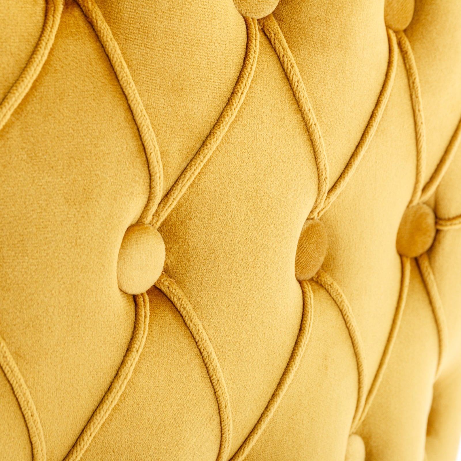 Closeup of mustard yellow velvet upholstery with diamond tufting and piping