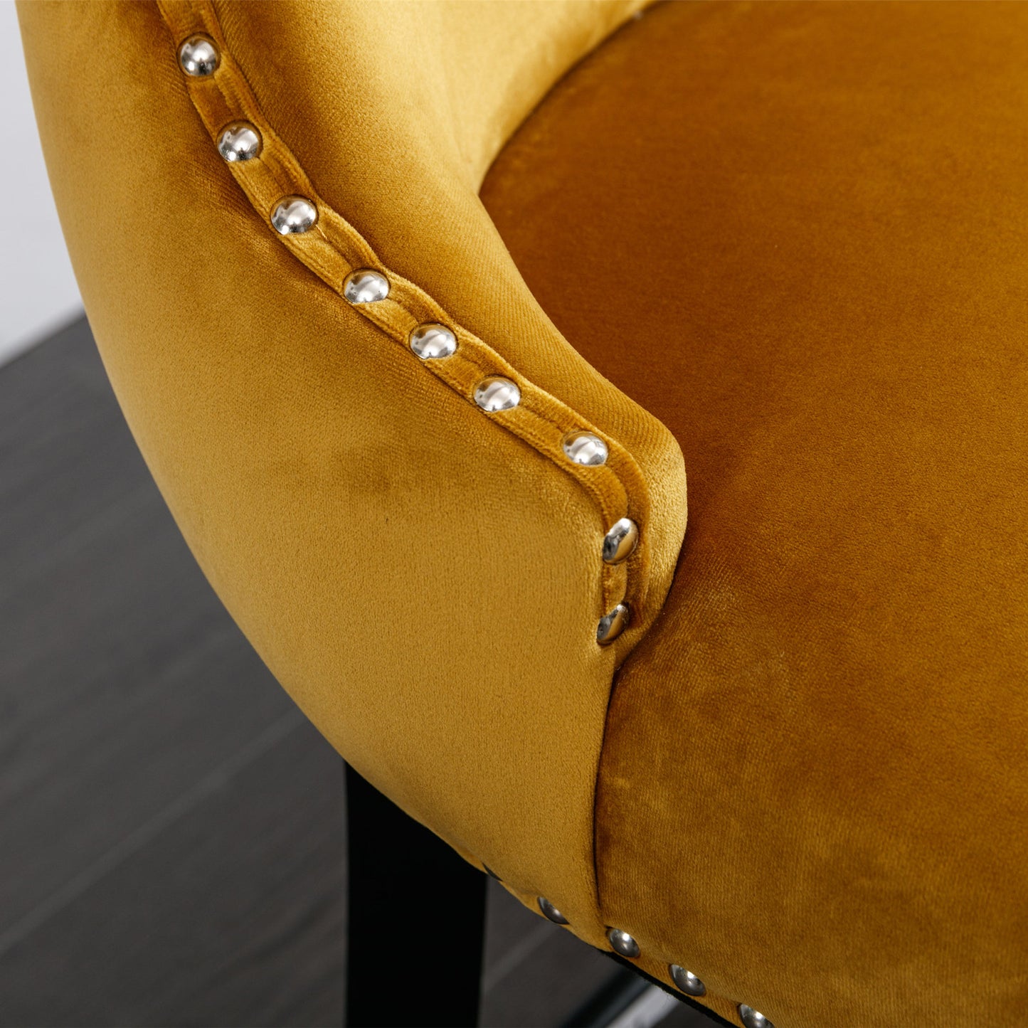 Closeup of mustard velvet armchair armrest with silver nailhead trim