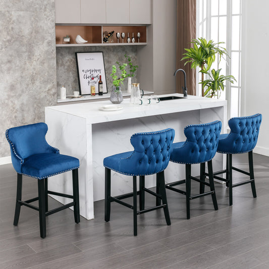 Four luxurious sapphire velvet tufted bar stools with silver nailhead trim around the seat and back