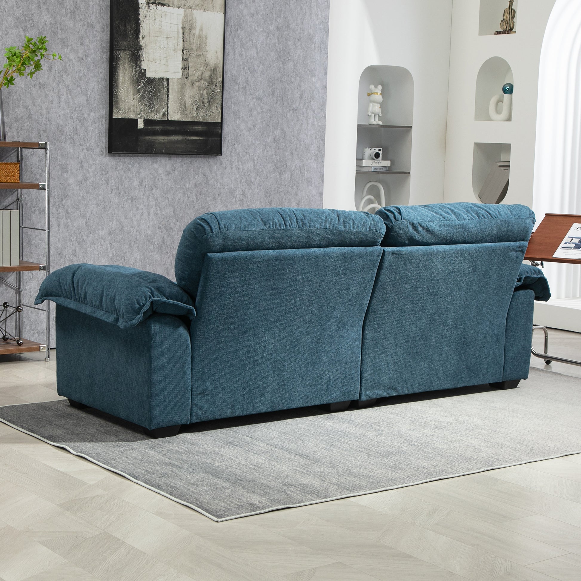 Plush teal fabric reclining sofa showing back view with padded armrests and headrests