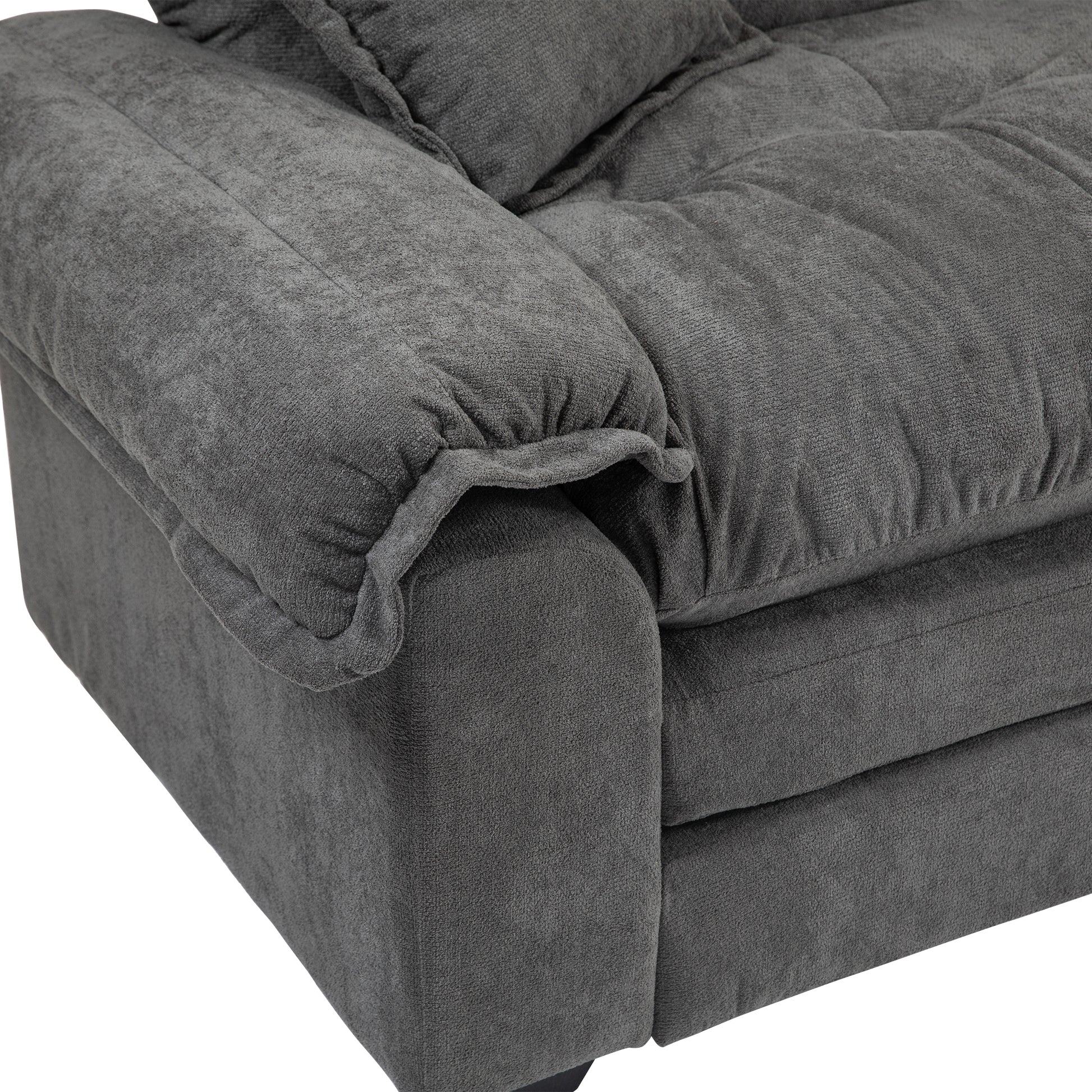 Closeup of a tufted charcoal grey chenille sofa armrest with plush cushions