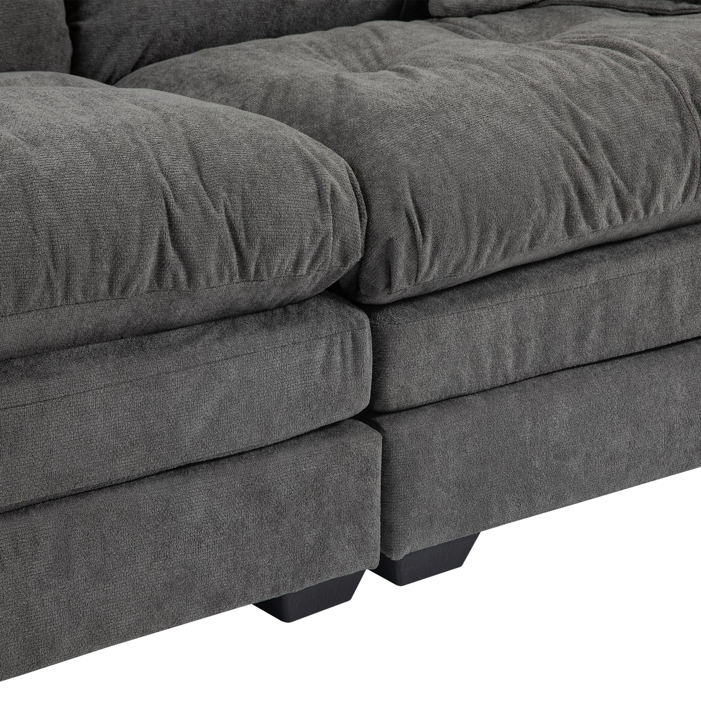 Closeup of plush charcoal gray fabric sofa cushions with deep tufting and sturdy black legs