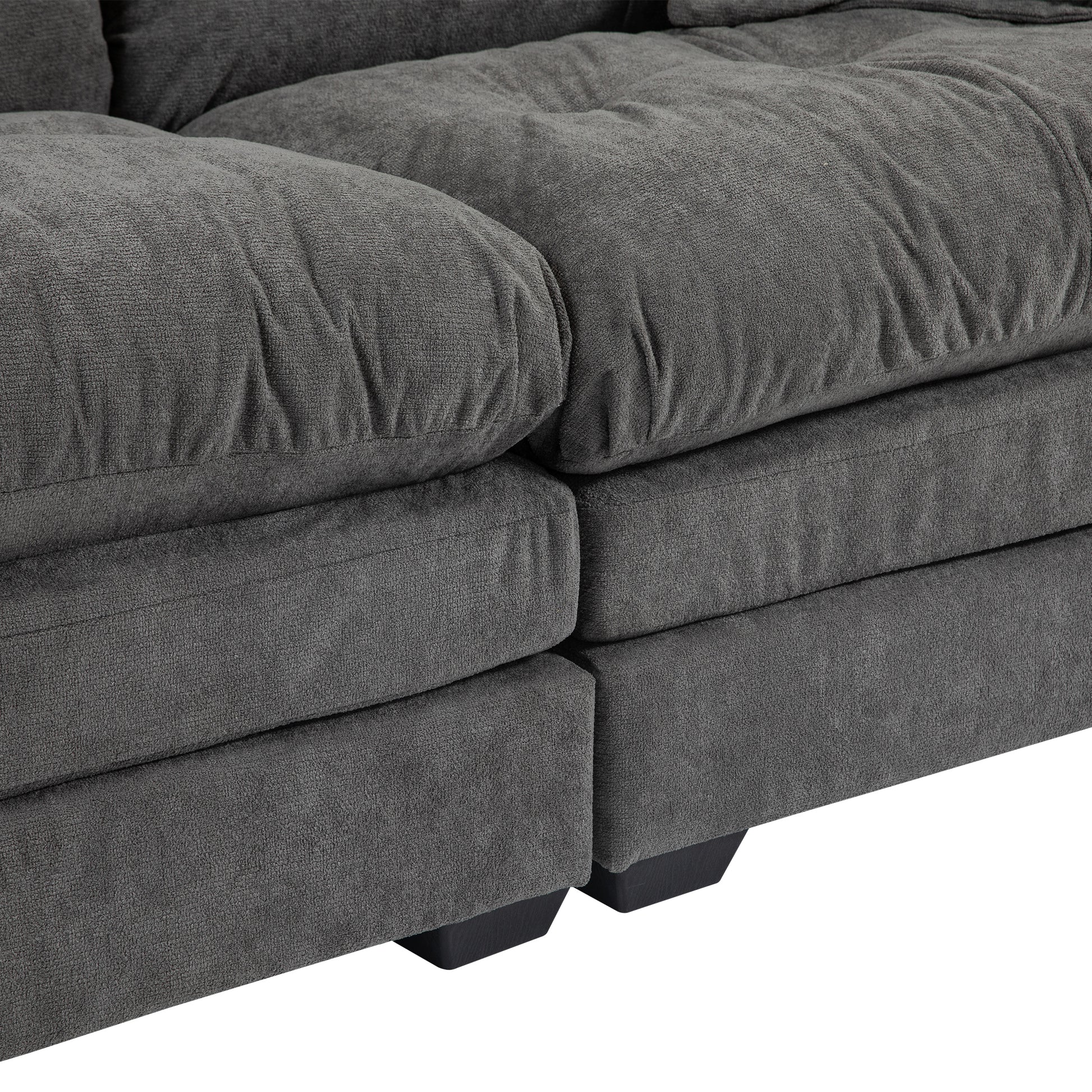 Closeup of plush charcoal gray fabric sofa cushions with deep tufting and sturdy black legs