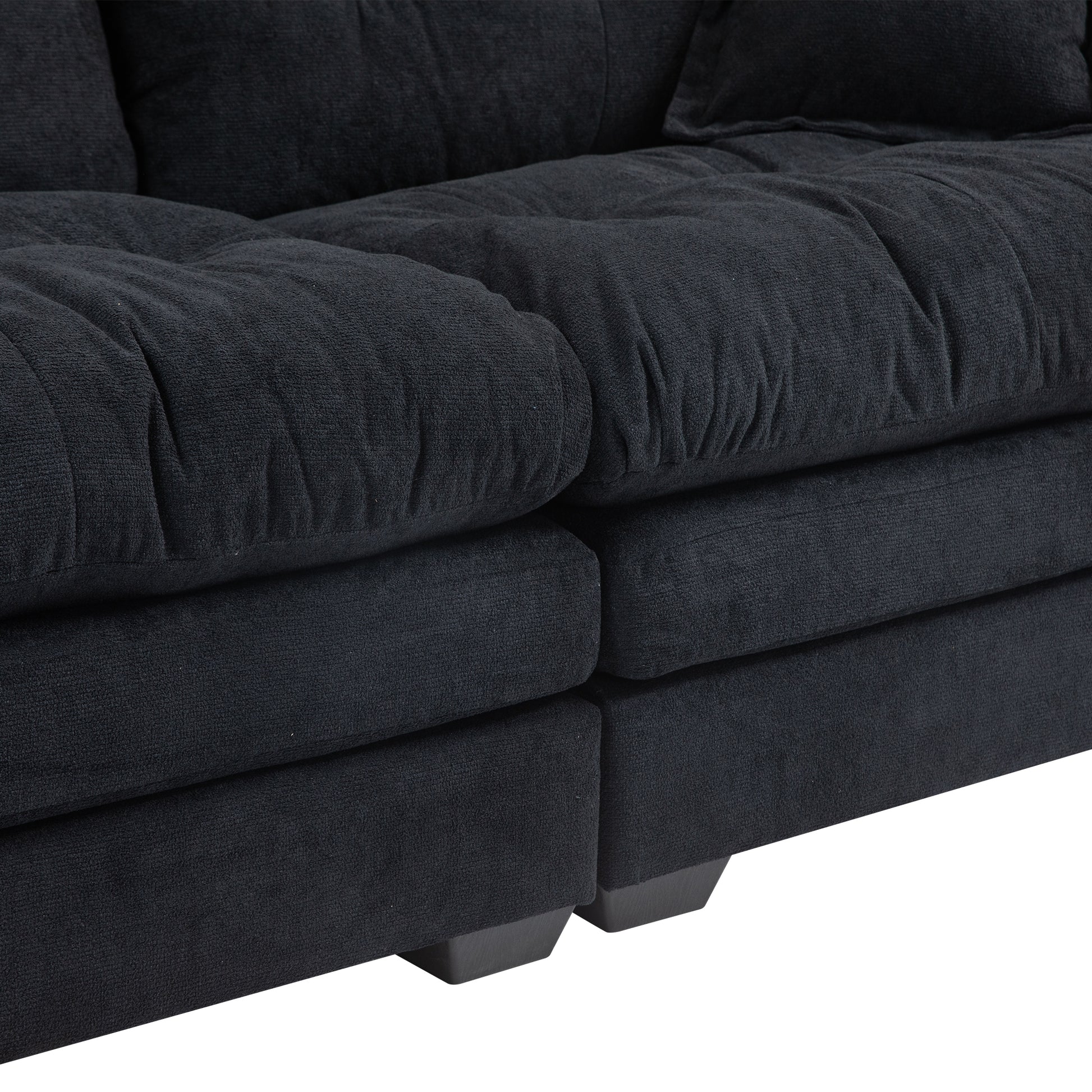 Textured dark grey fabric sofa with plush tufted cushions and dark wood legs