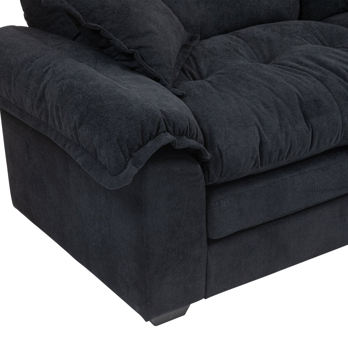 Closeup of a plush charcoal grey fabric sofa armrest with tufted cushions and a soft texture