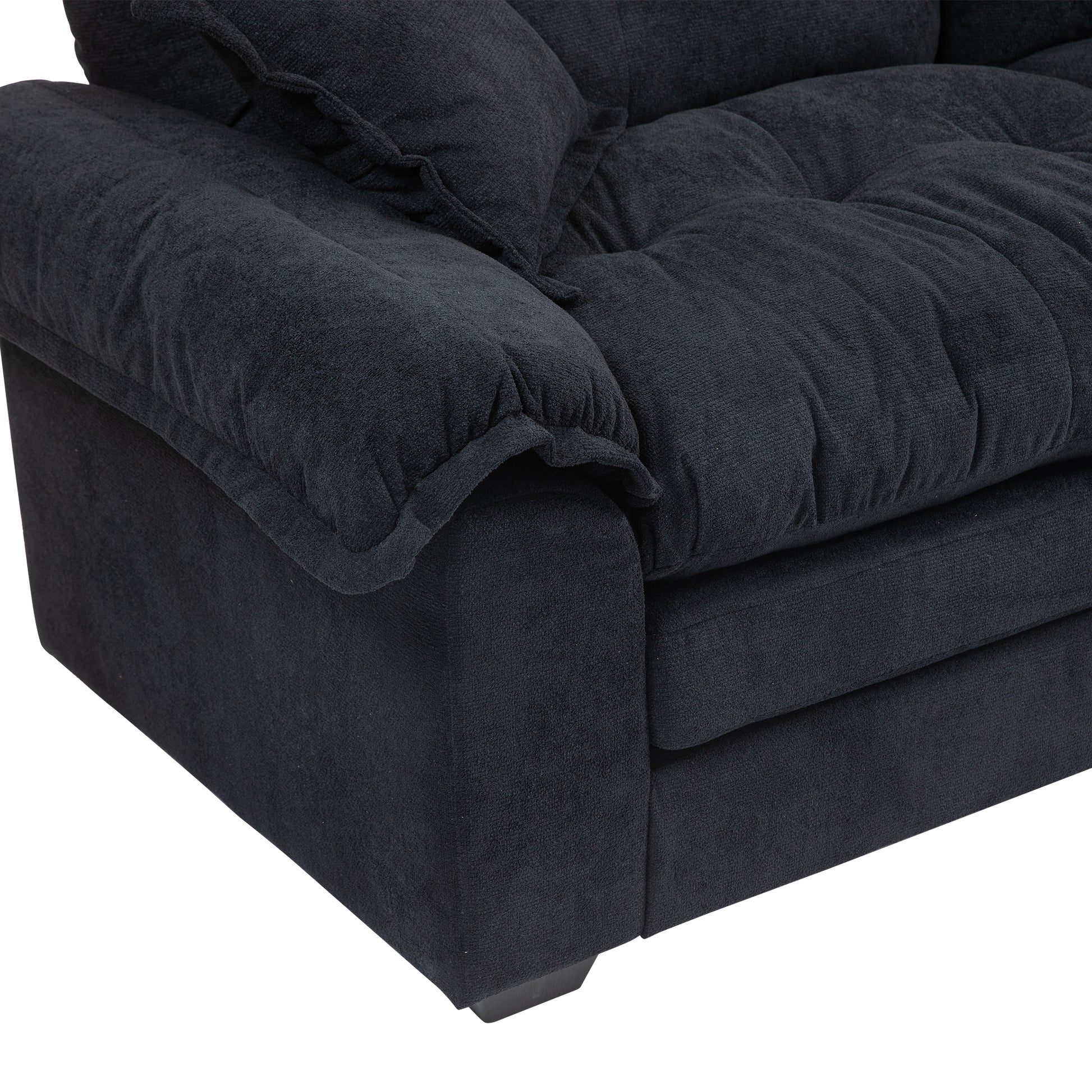 Closeup of a plush charcoal grey fabric sofa armrest with tufted cushions and a soft texture