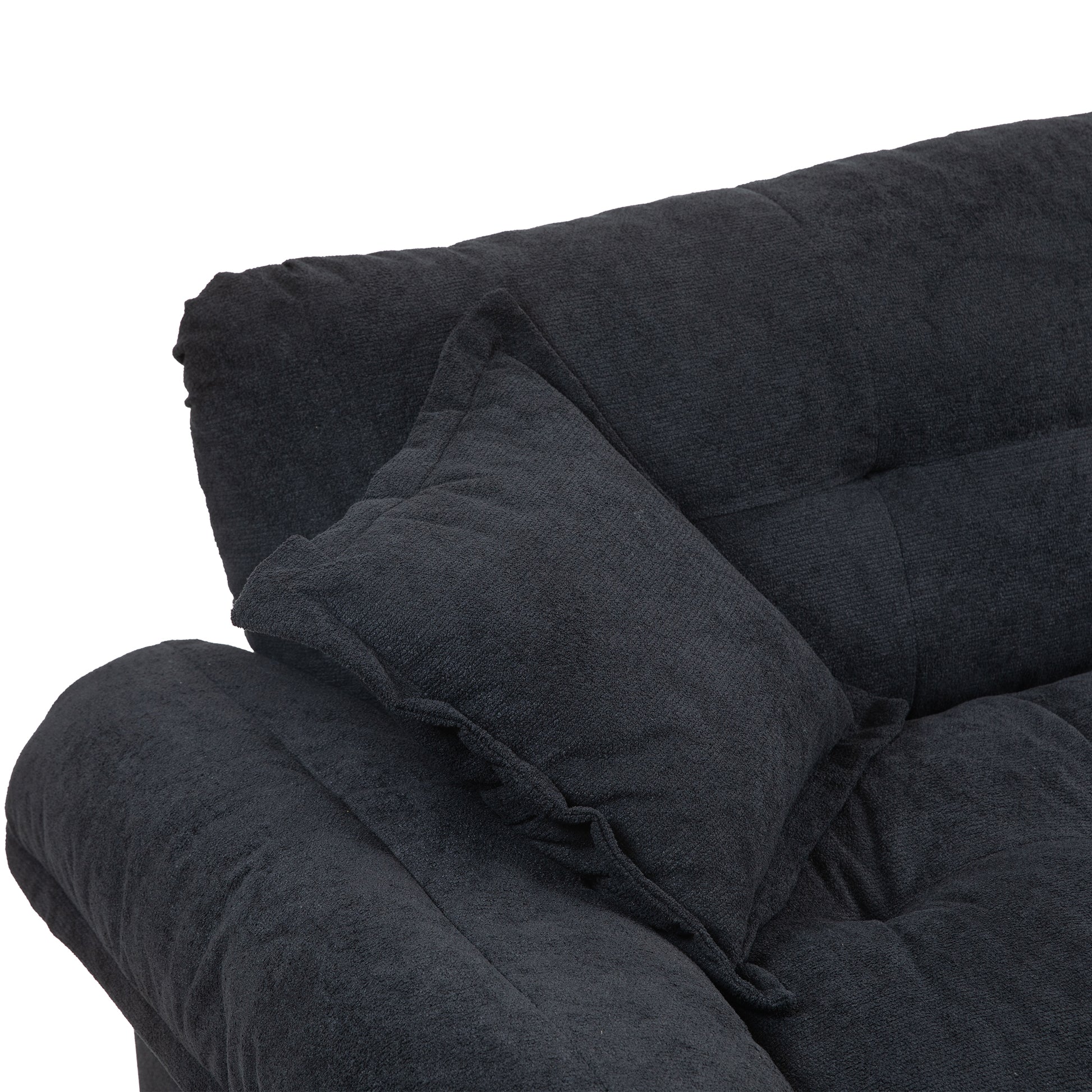 Closeup of a dark gray fabric sofa corner with tufted backrest and a matching throw pillow