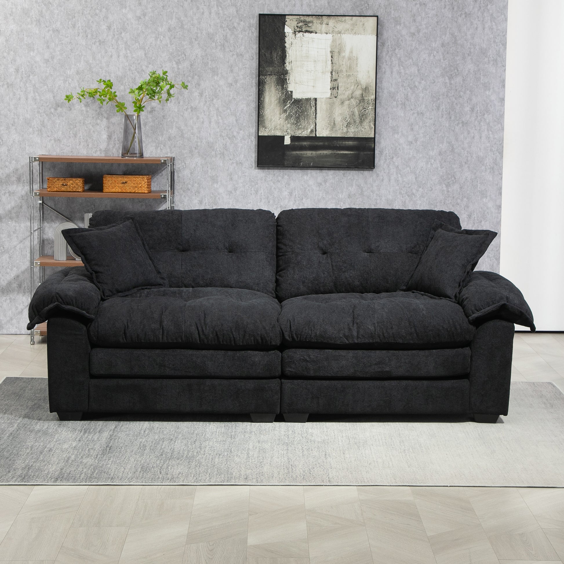Dark gray fabric sofa with plush cushions and tufted details on a light wood floor