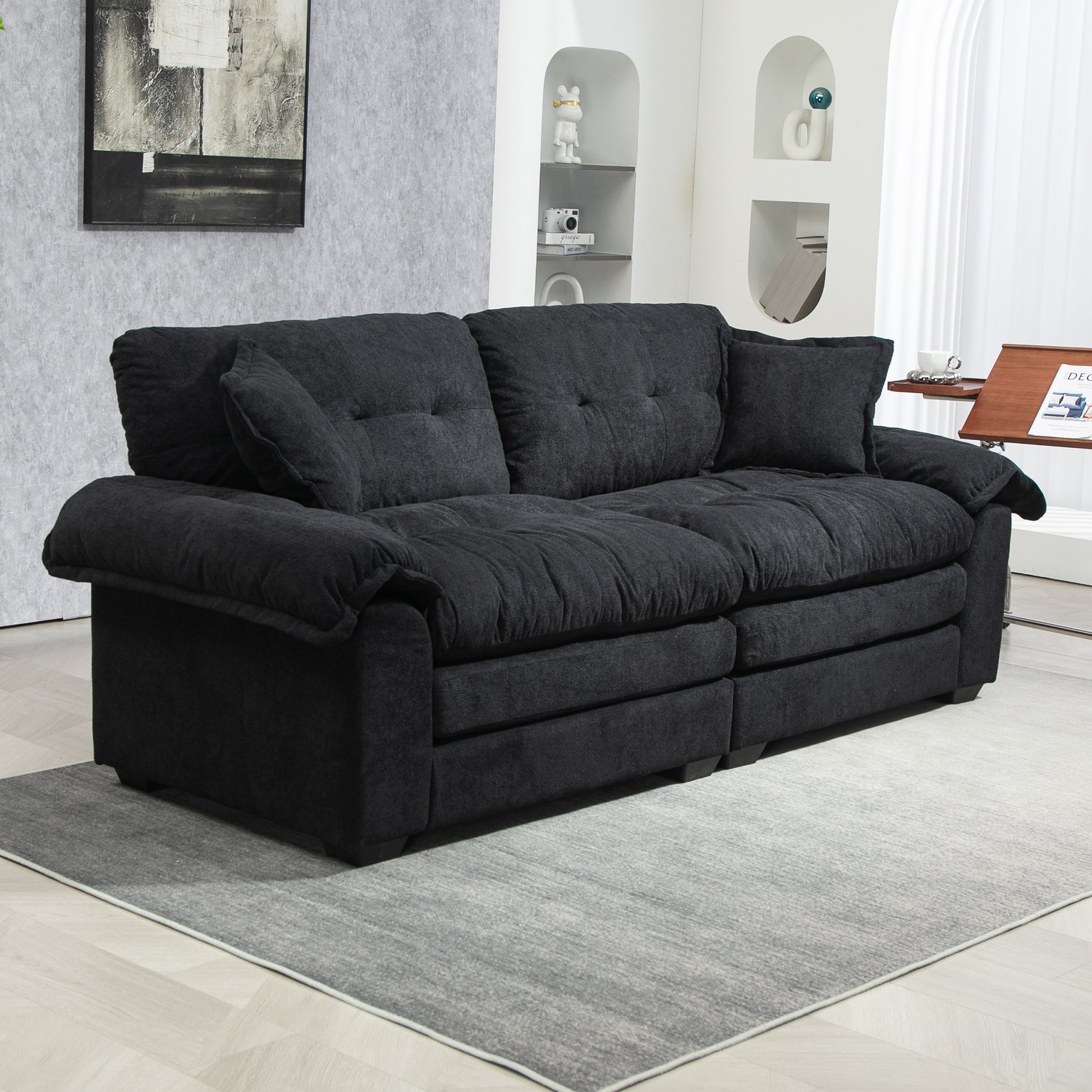 Plush dark charcoal fabric couch with tufted cushions and rolled arms