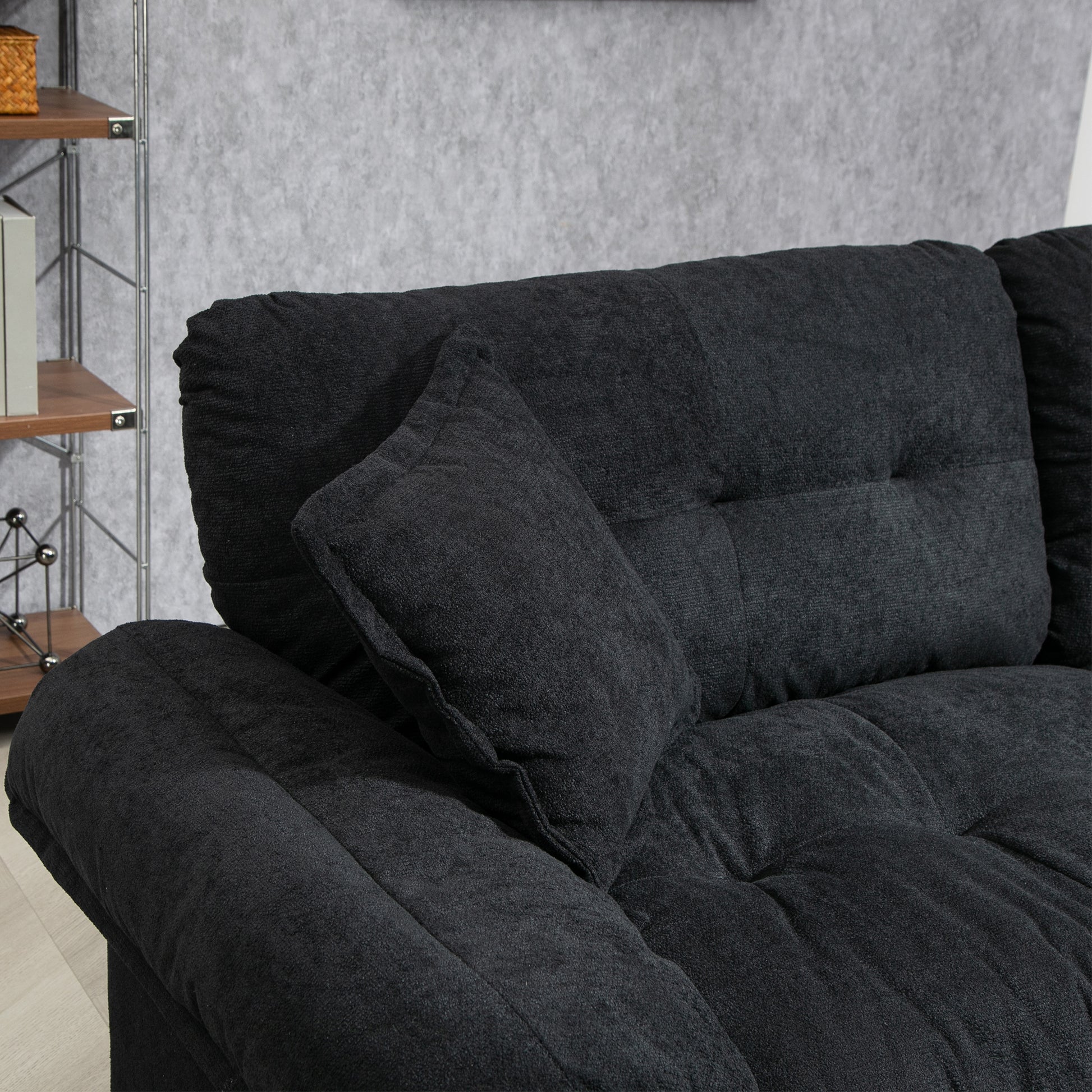 Closeup of a plush dark grey sofa with tufted cushions and a comfortable throw pillow
