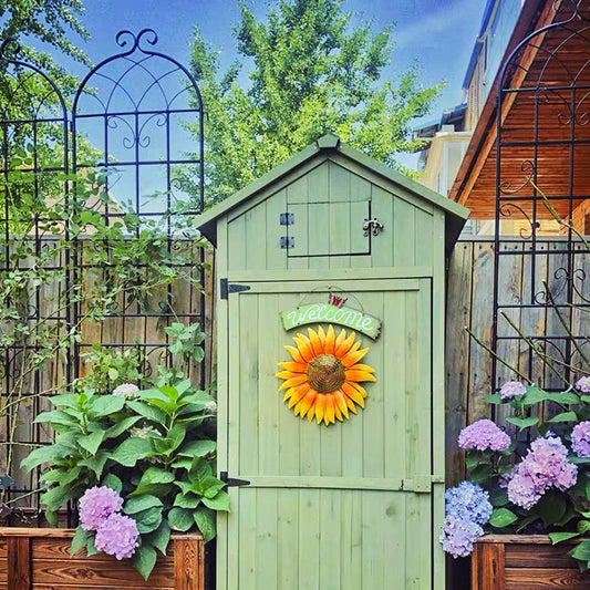 Green wooden garden shed with sunflower decoration and hydrangea plants