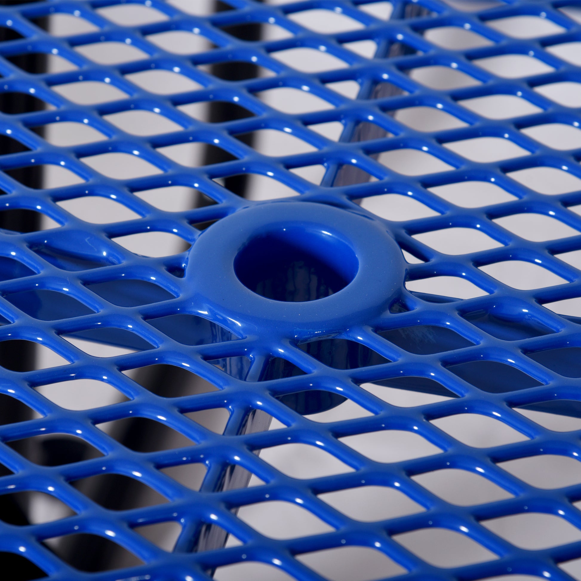 Vibrant blue expanded metal mesh table surface with integrated drink holder detail