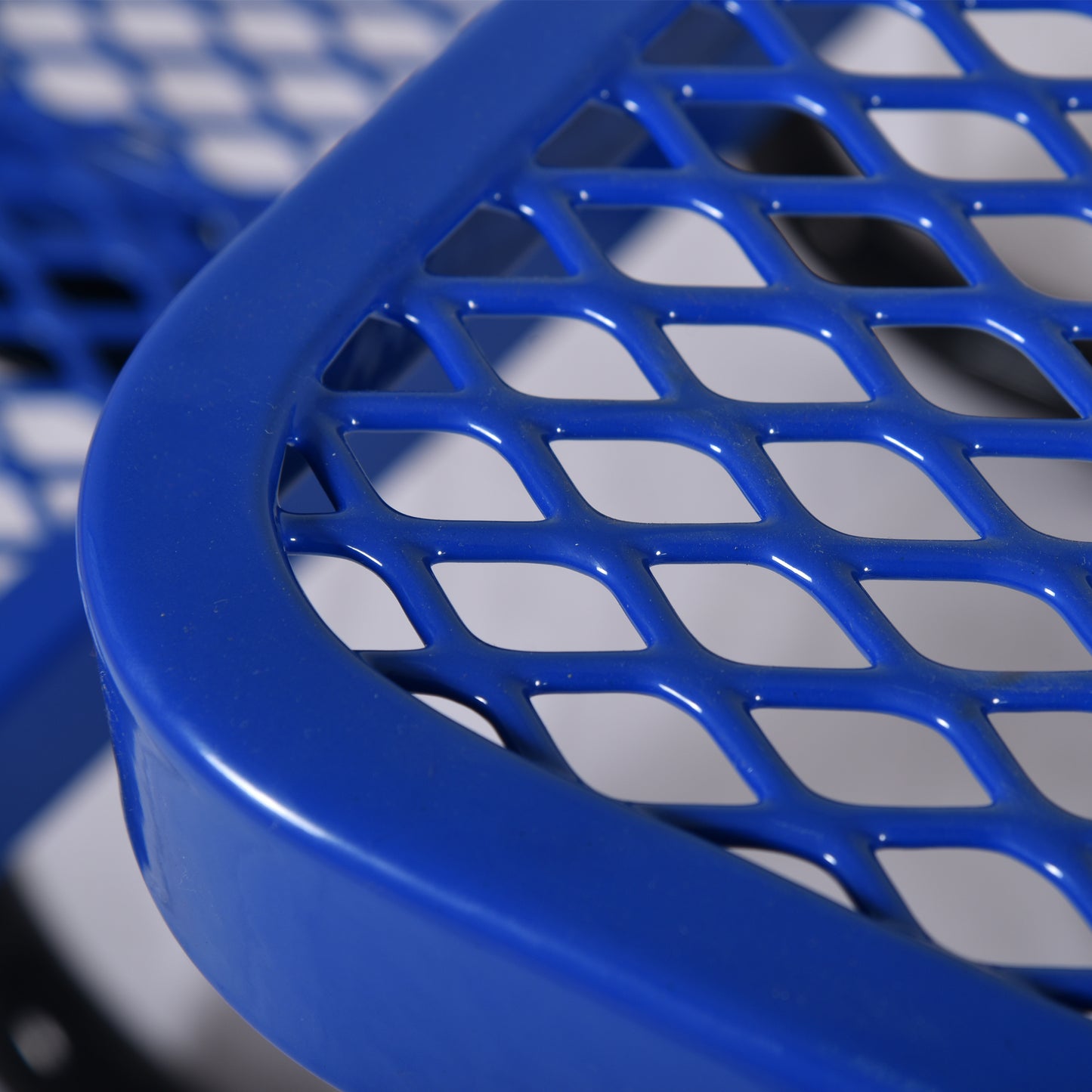 Closeup of a bright blue metal bench with a diamond pattern perforated seat