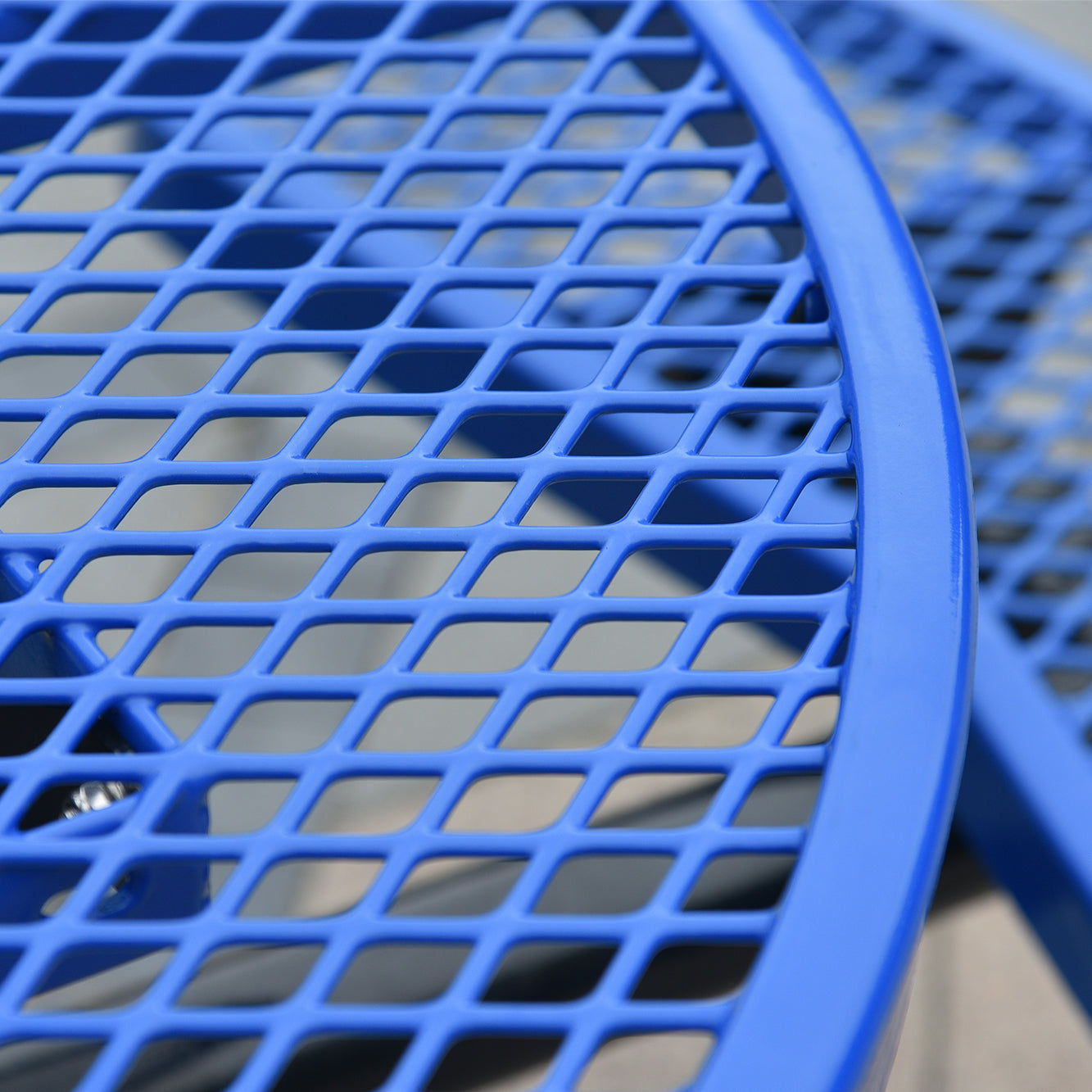Closeup of a bright blue metal mesh outdoor table surface with diamondshaped openings