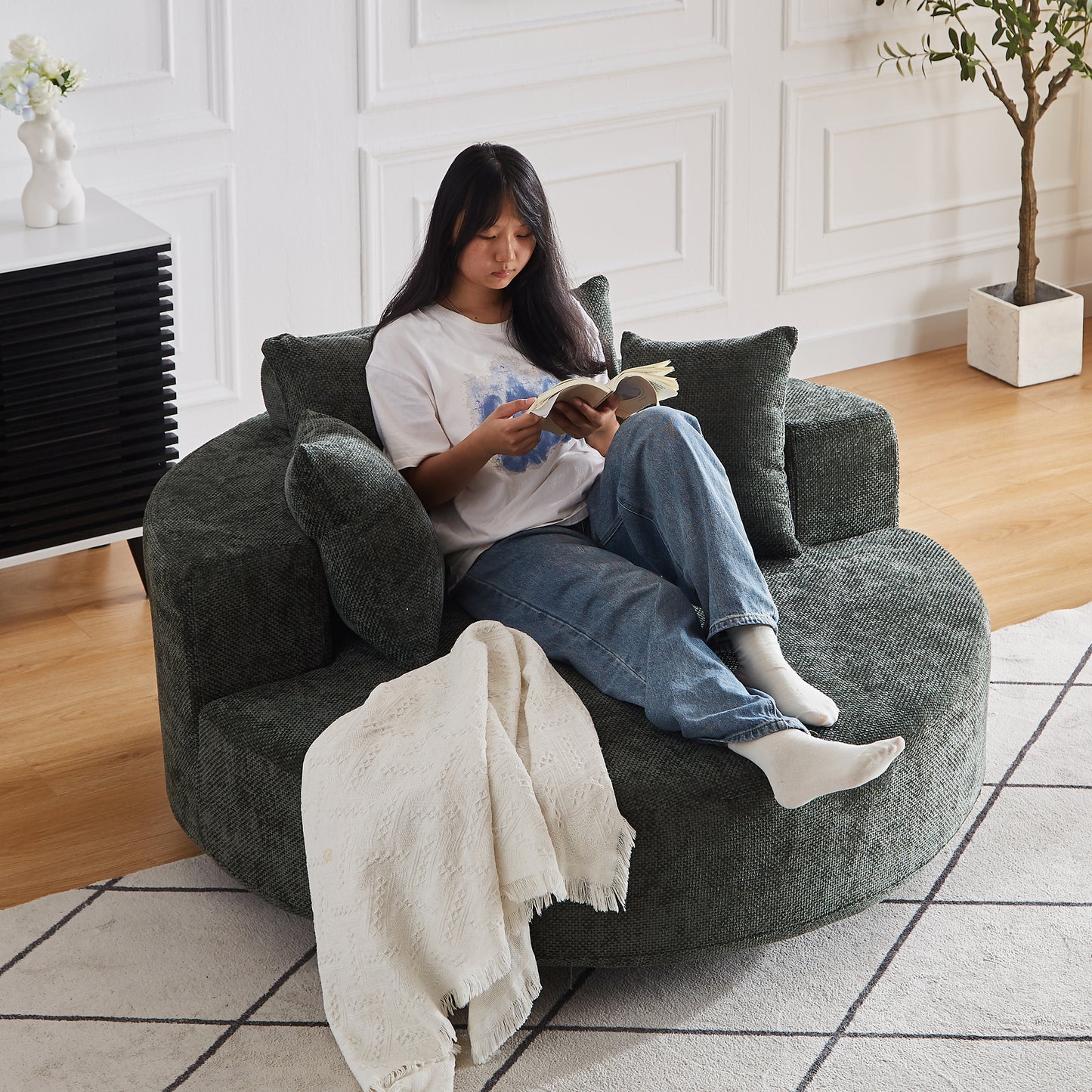 Dark green textured circular accent chair with plush cushions and a white throw blanket