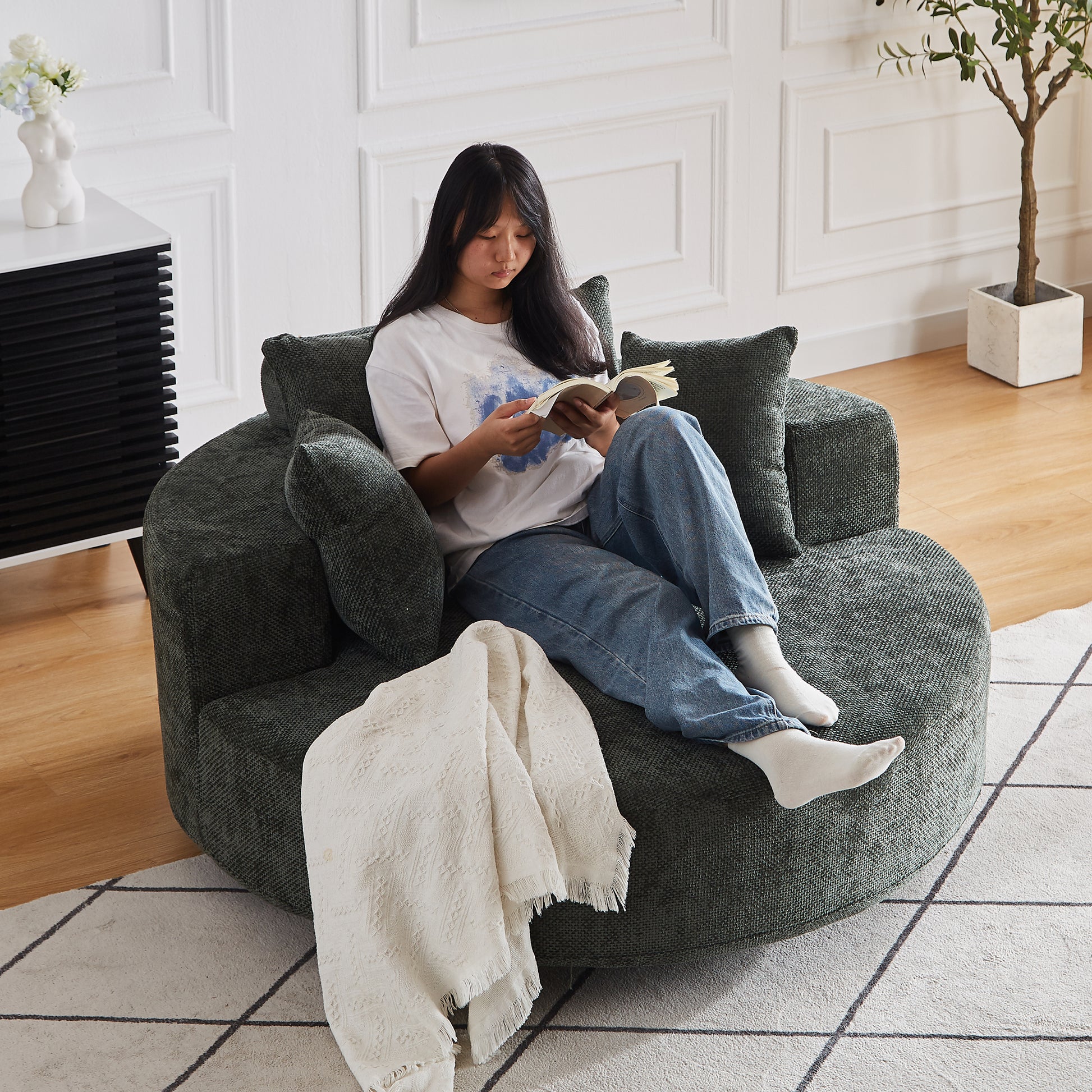 Dark green textured circular accent chair with plush cushions and a white throw blanket