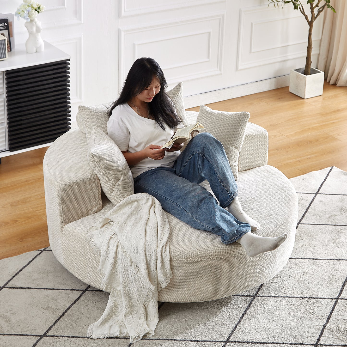 Cozy circular cream boucl accent chair with plush cushions and a throw blanket