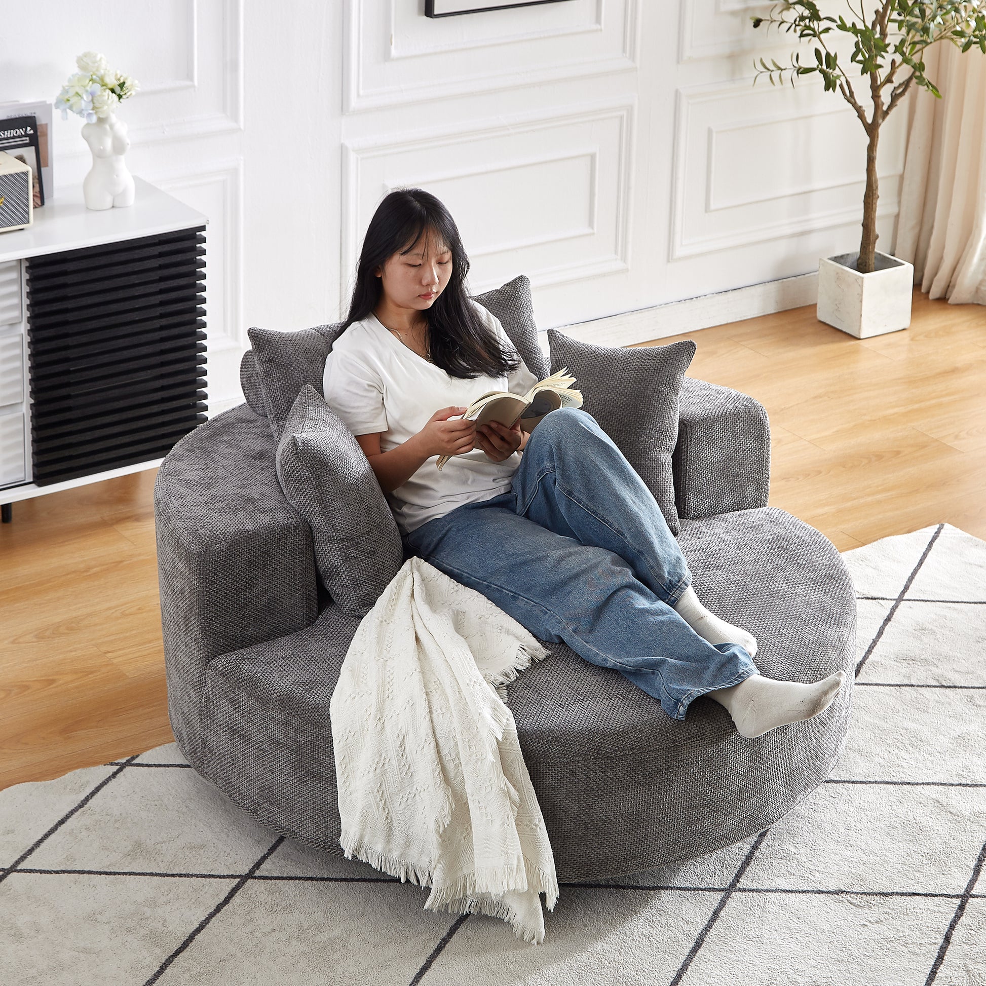 Plush grey swivel accent chair with a relaxed woman reading a book