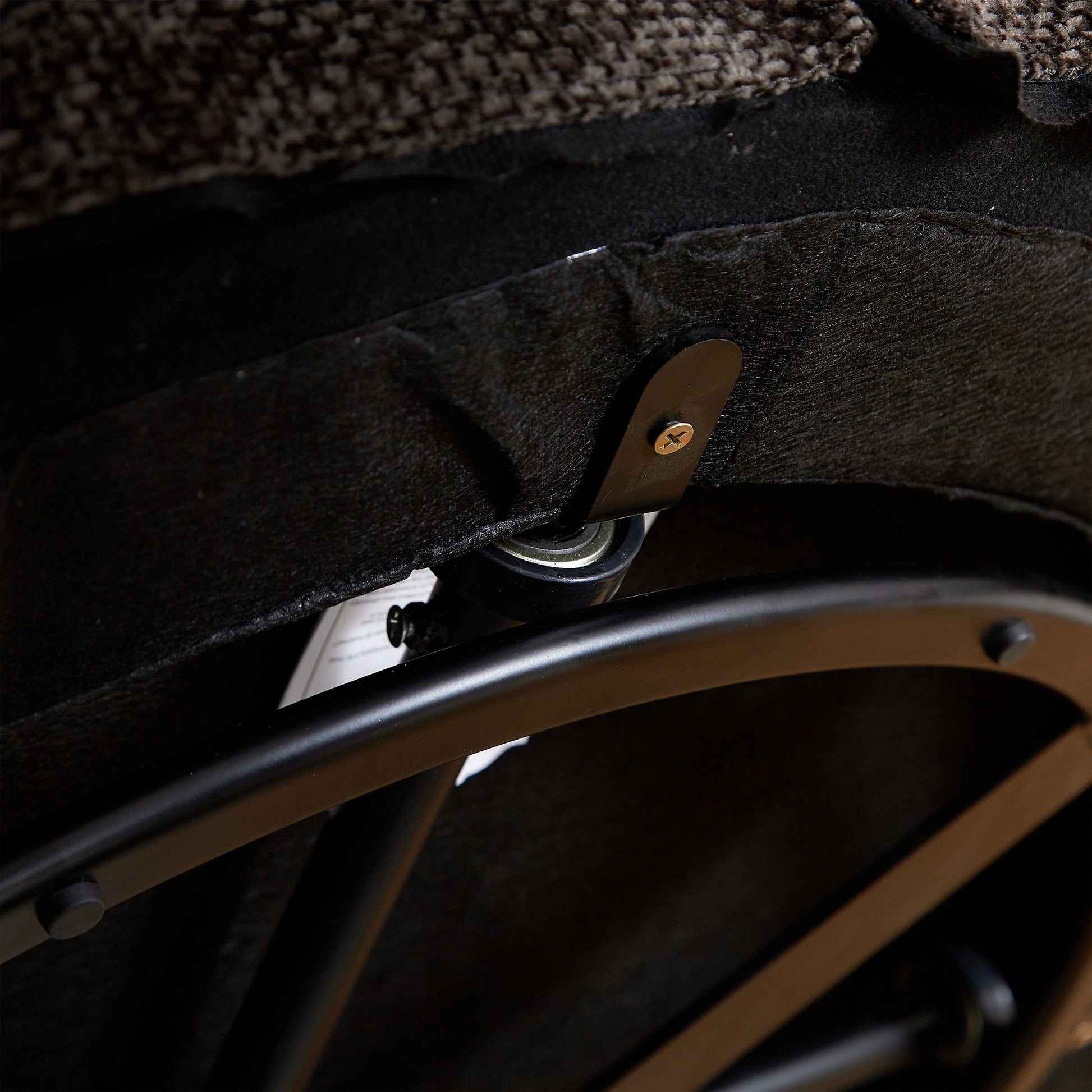 Brown tweed fabric detail on chair base with black metal caster wheel and screw