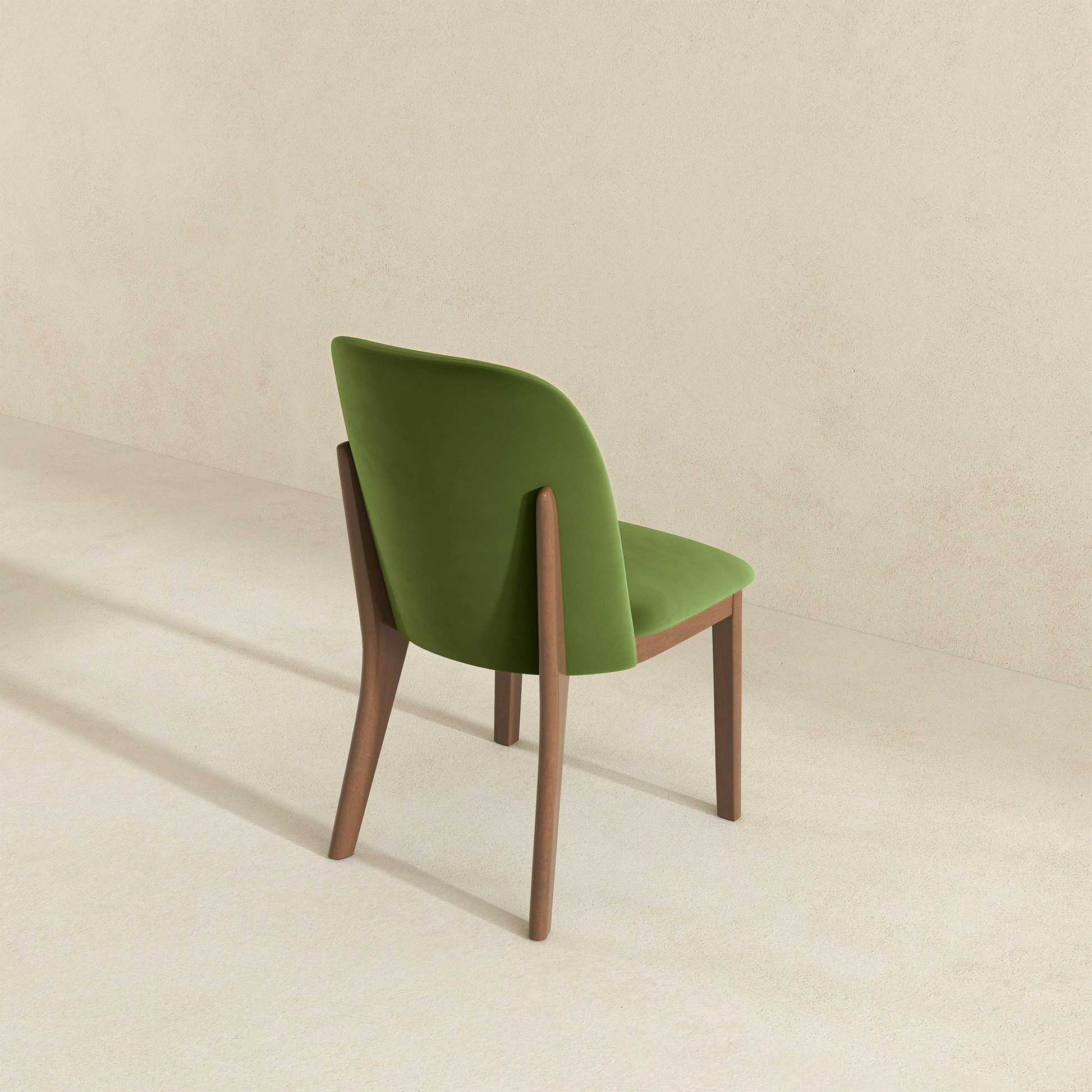 Modern green velvet dining chair with elegant wooden legs and a curved backrest