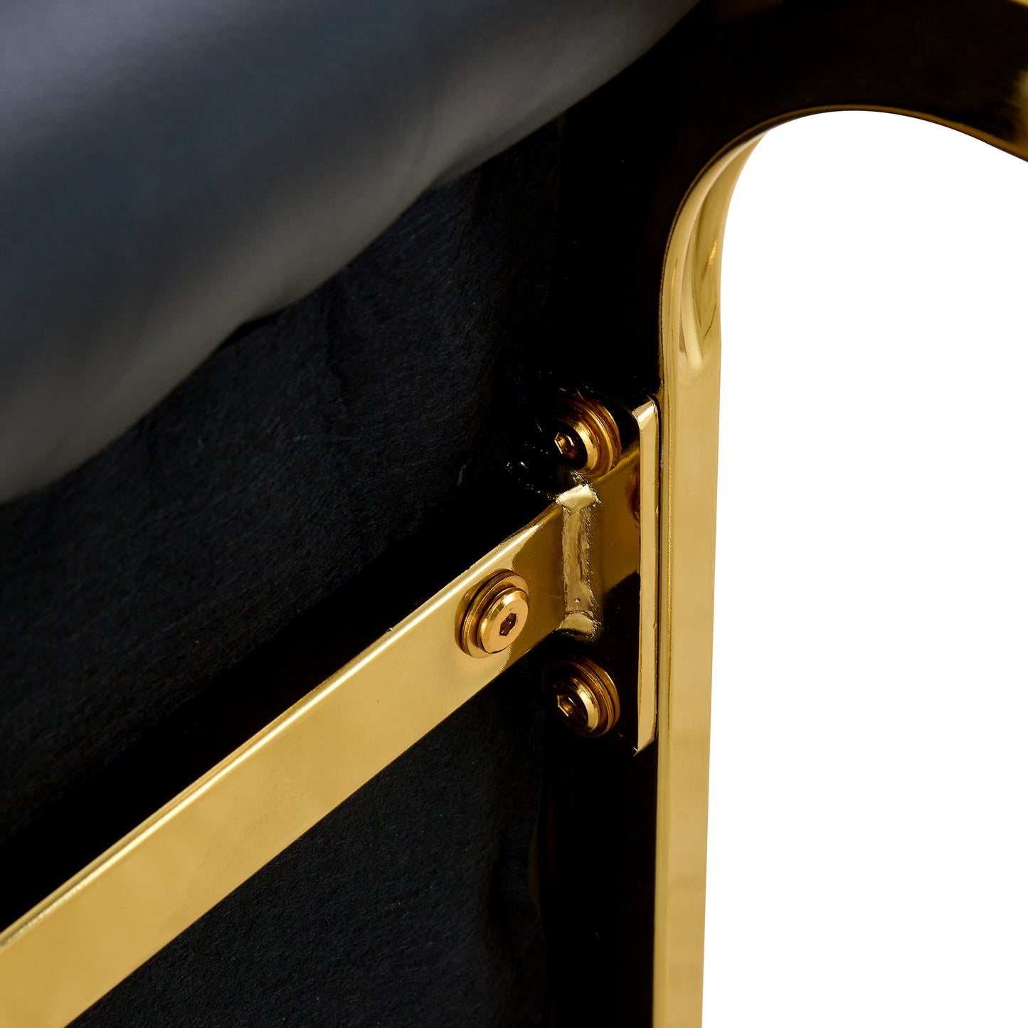 Closeup of a goldplated chair frame with black upholstery and visible screws
