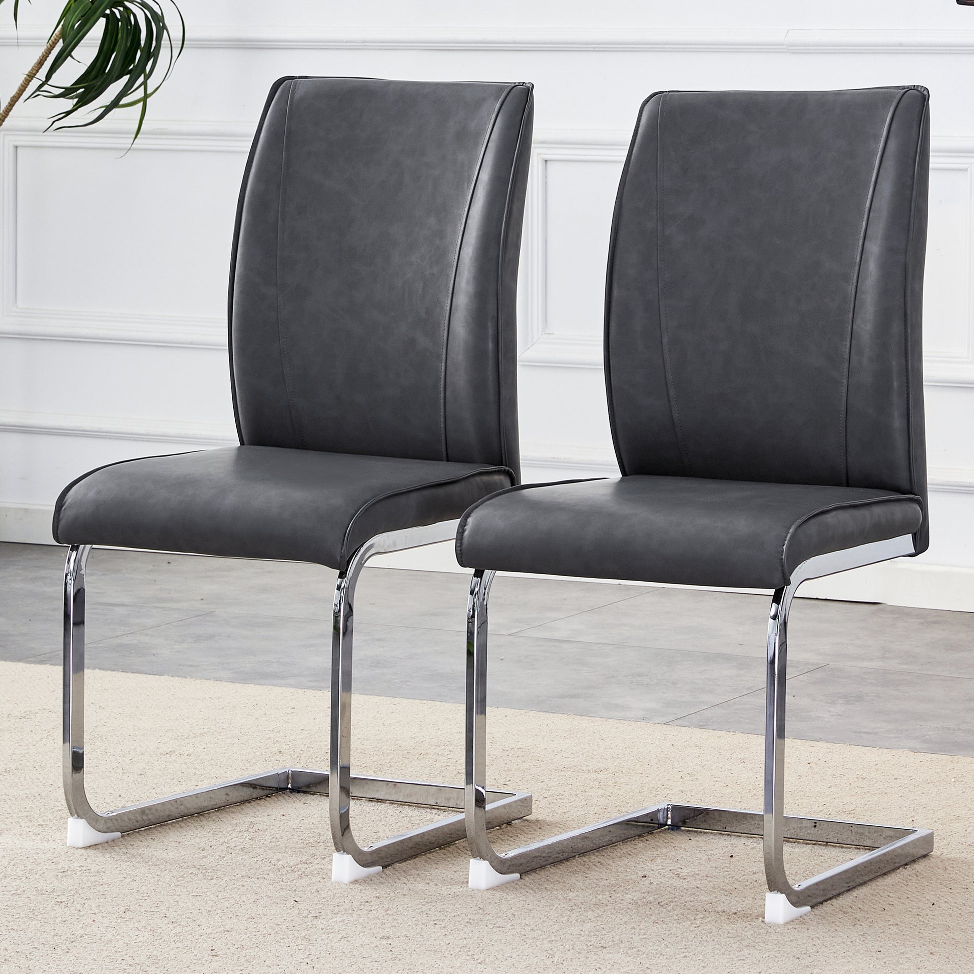 Two dark gray faux leather dining chairs with chrome cantilever bases