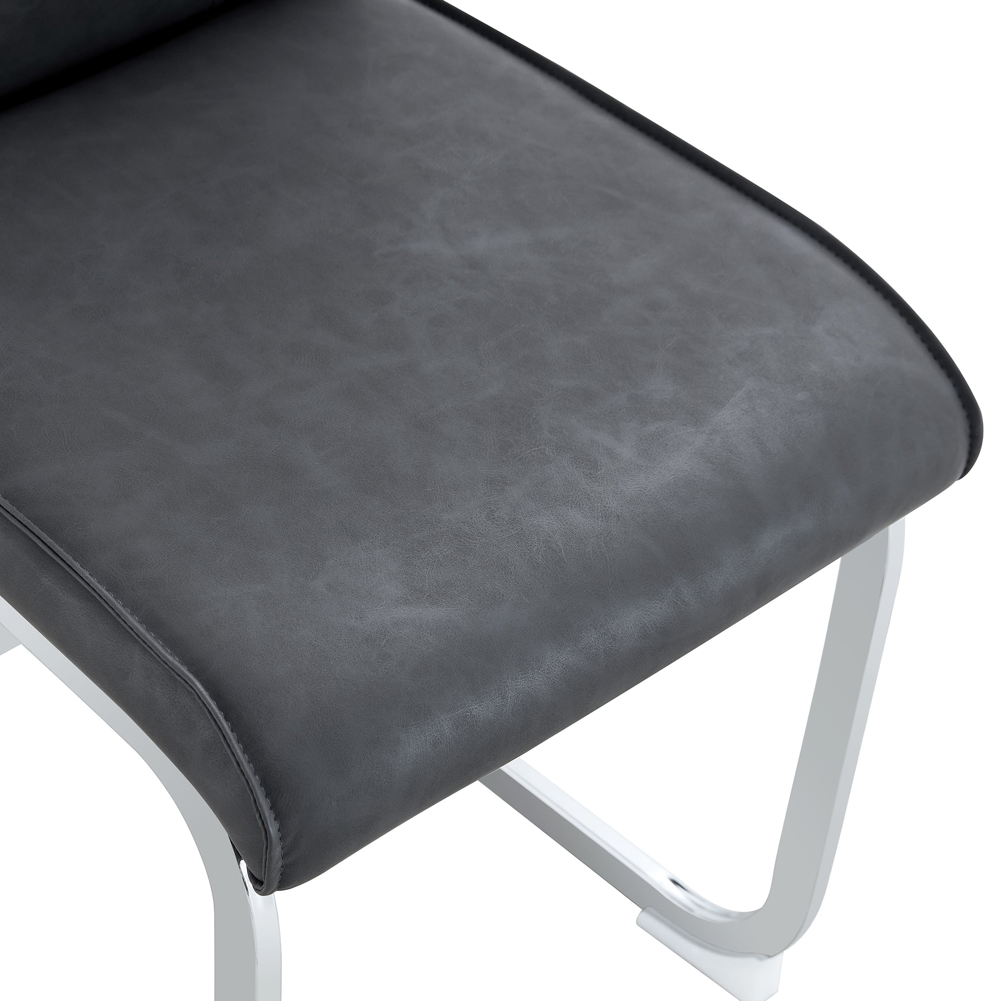 Closeup of a dark gray faux leather seat with white metal legs a modern accent chair