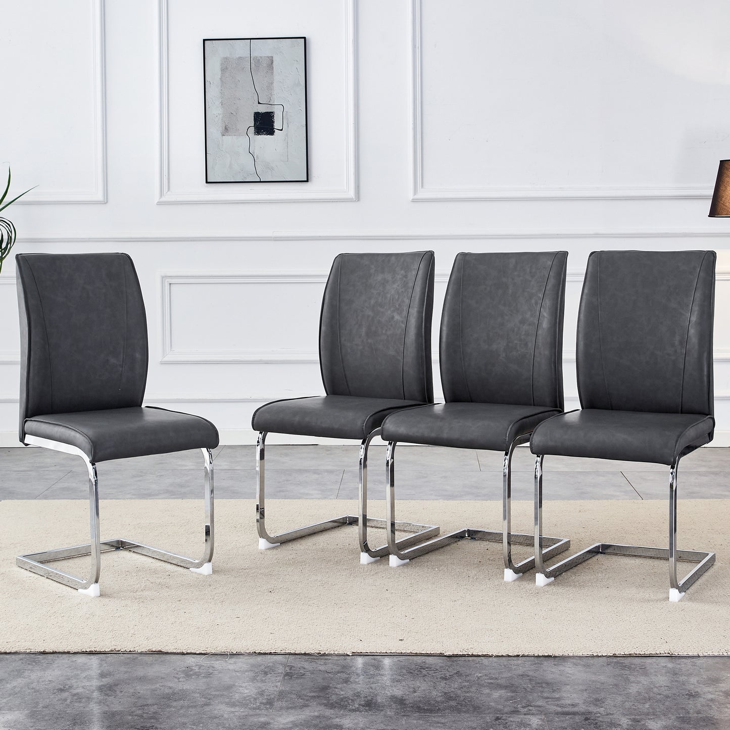 Four dark grey faux leather dining chairs with chrome sled legs arranged in a row