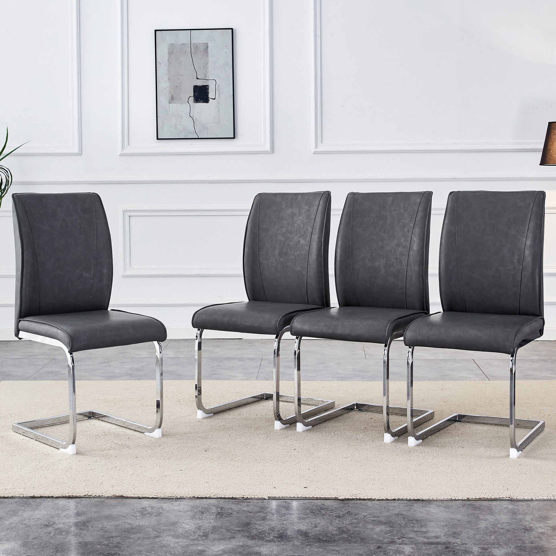 Four dark grey faux leather dining chairs with chrome sled legs arranged in a row