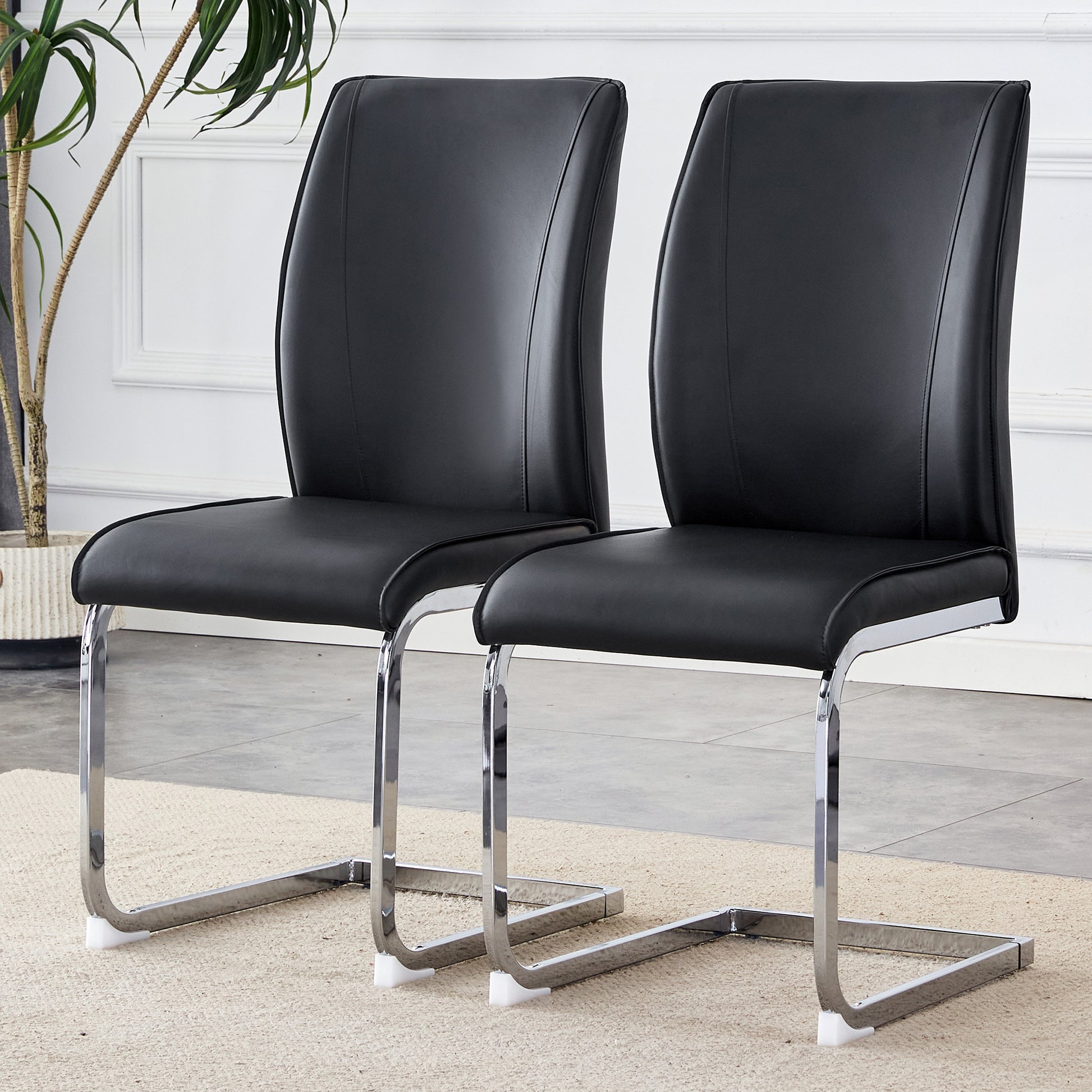 Two black leather dining chairs with chrome cantilever bases