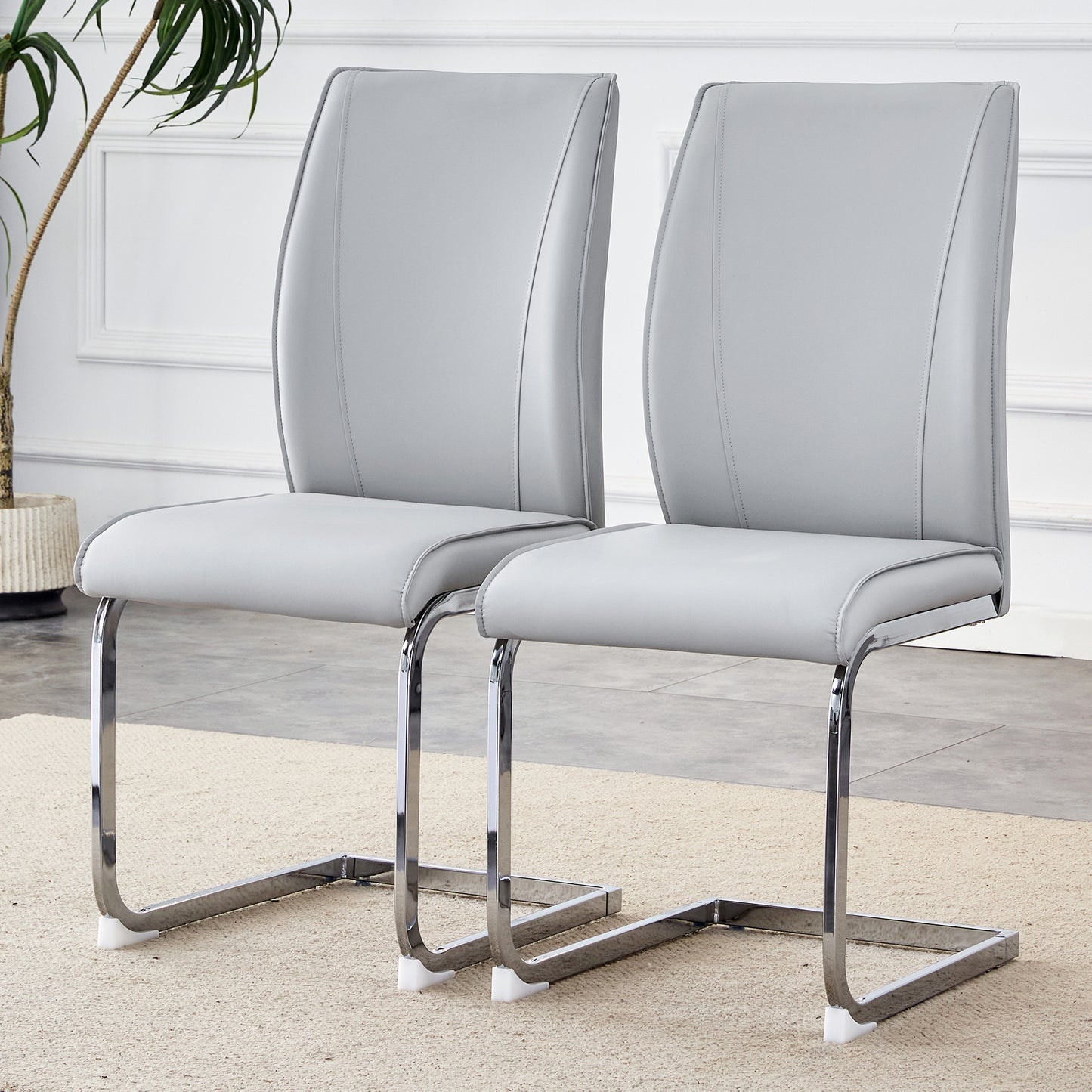 Two sleek grey faux leather dining chairs with chrome cantilever legs