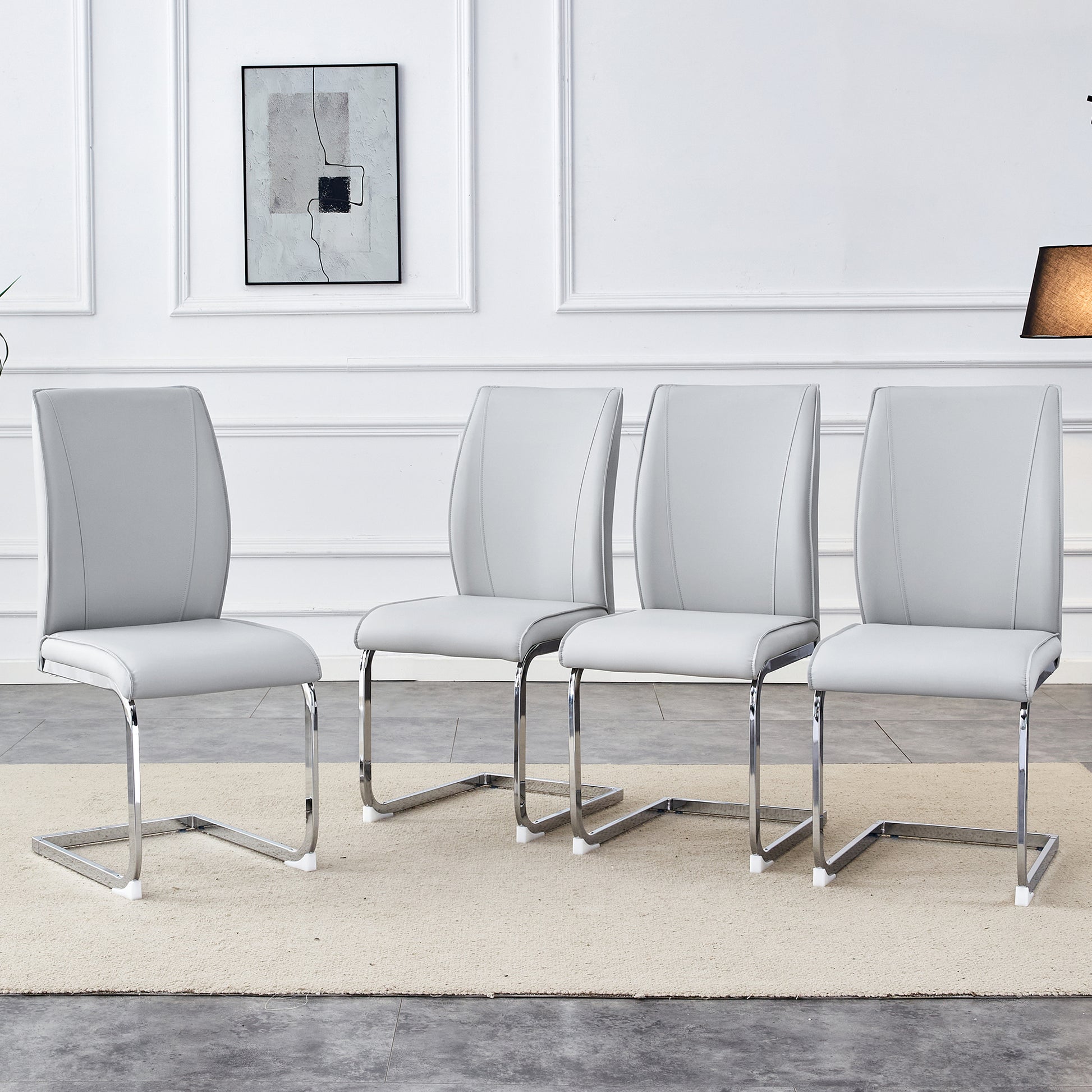 Four light grey faux leather dining chairs with chrome sled legs