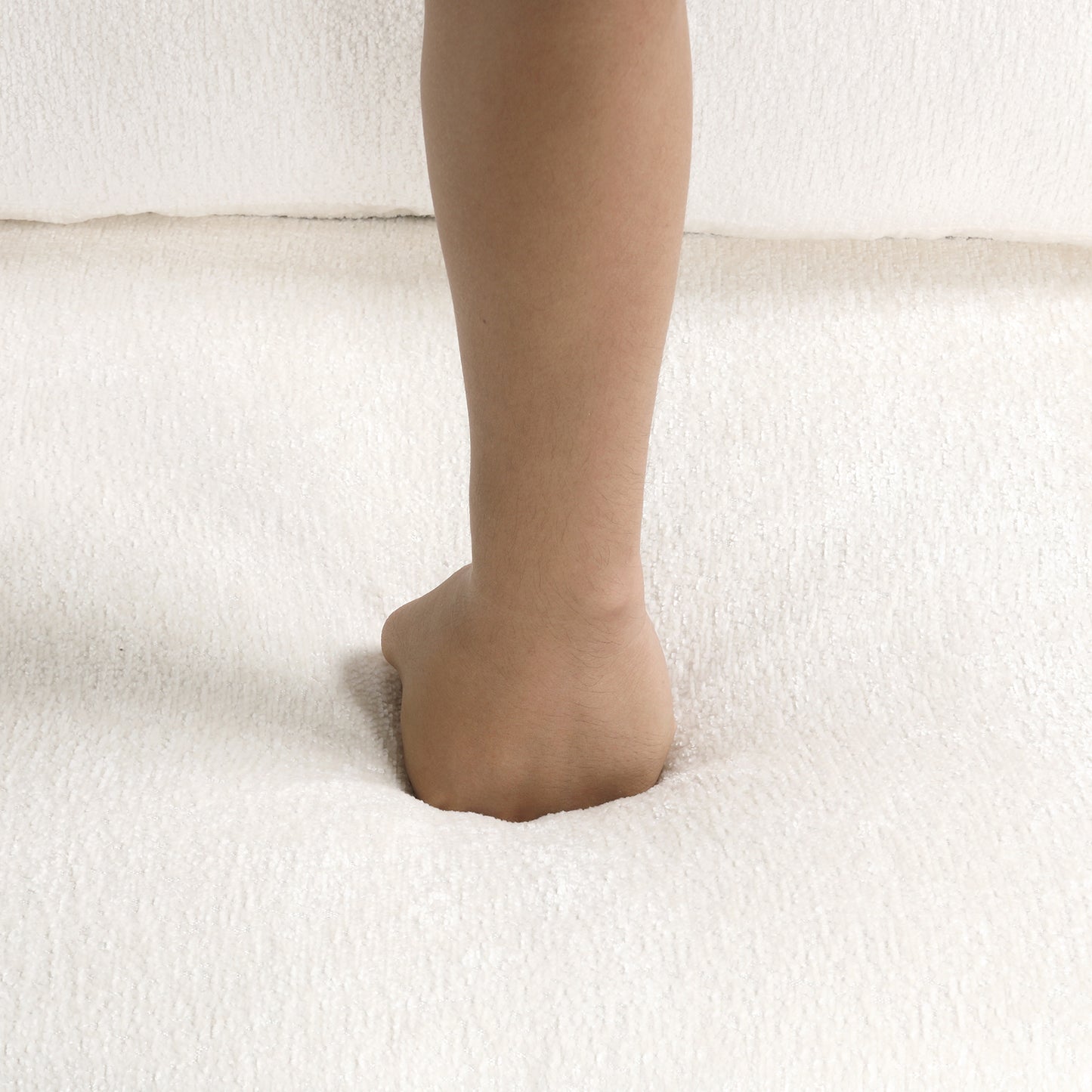 Persons foot pressing into plush white carpet demonstrating softness