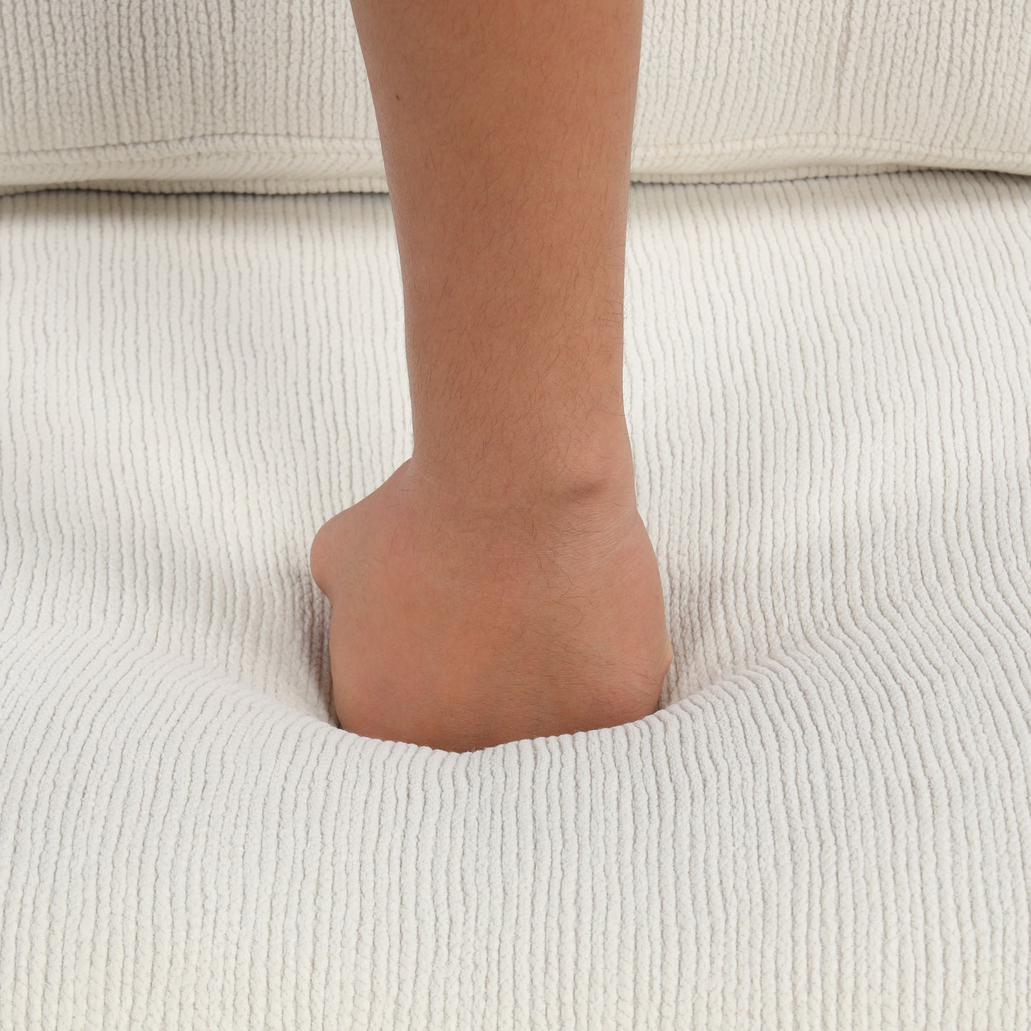 Hand pressing into soft creamcolored corduroy fabric sofa
