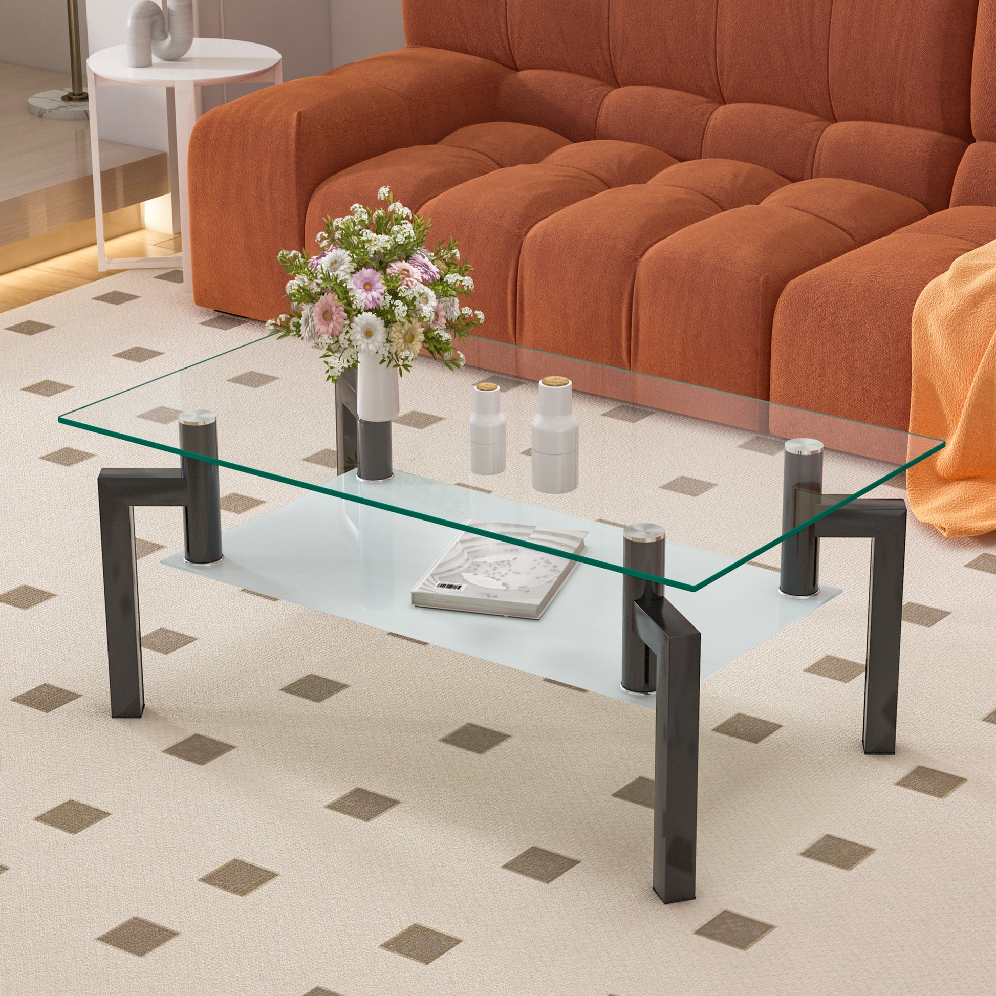 Clear glass coffee table with a modern metallic frame and a decorative book