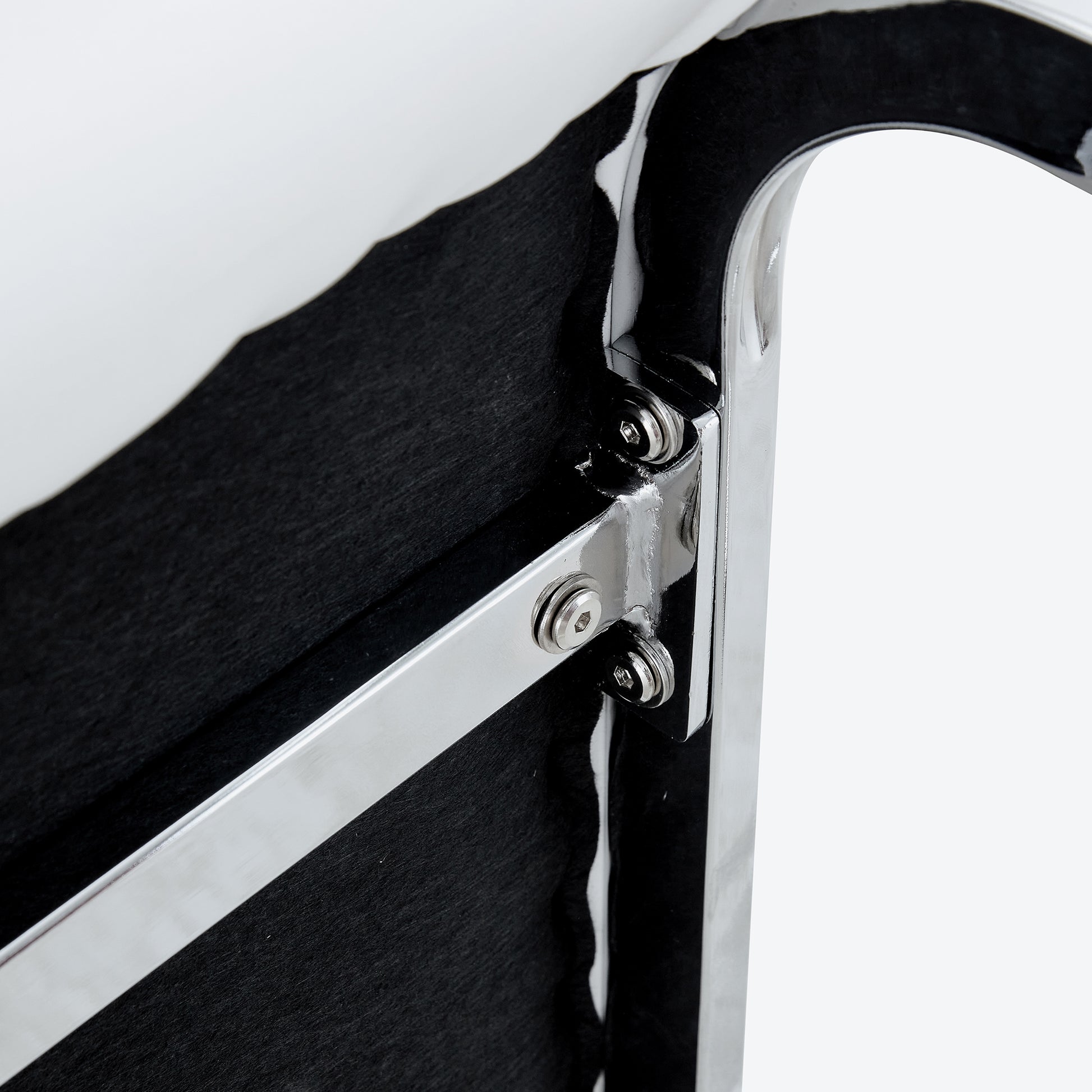 Closeup of chromeplated metal frame with black textured fabric backing showing secure bolt attachments for durability