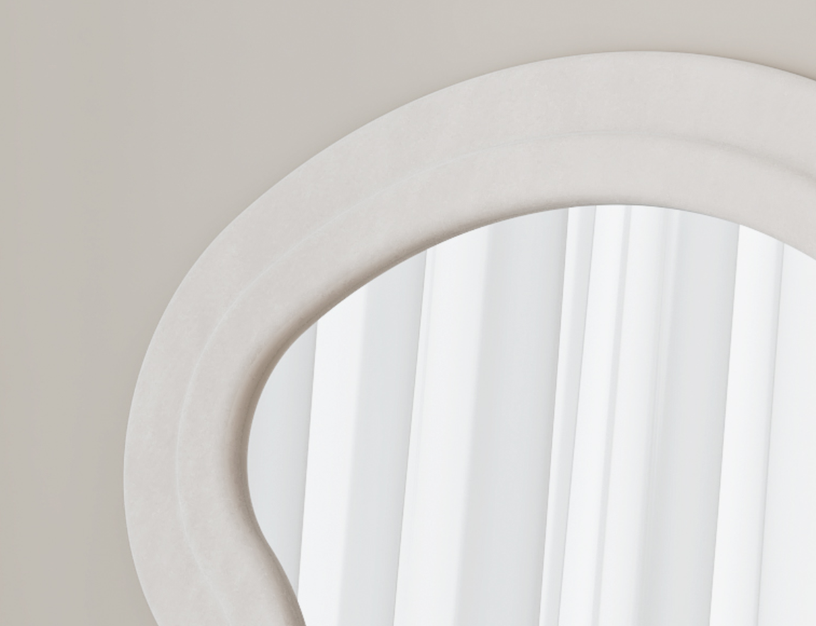 Abstract organic shaped mirror with textured ivory frame reflecting soft white curtains